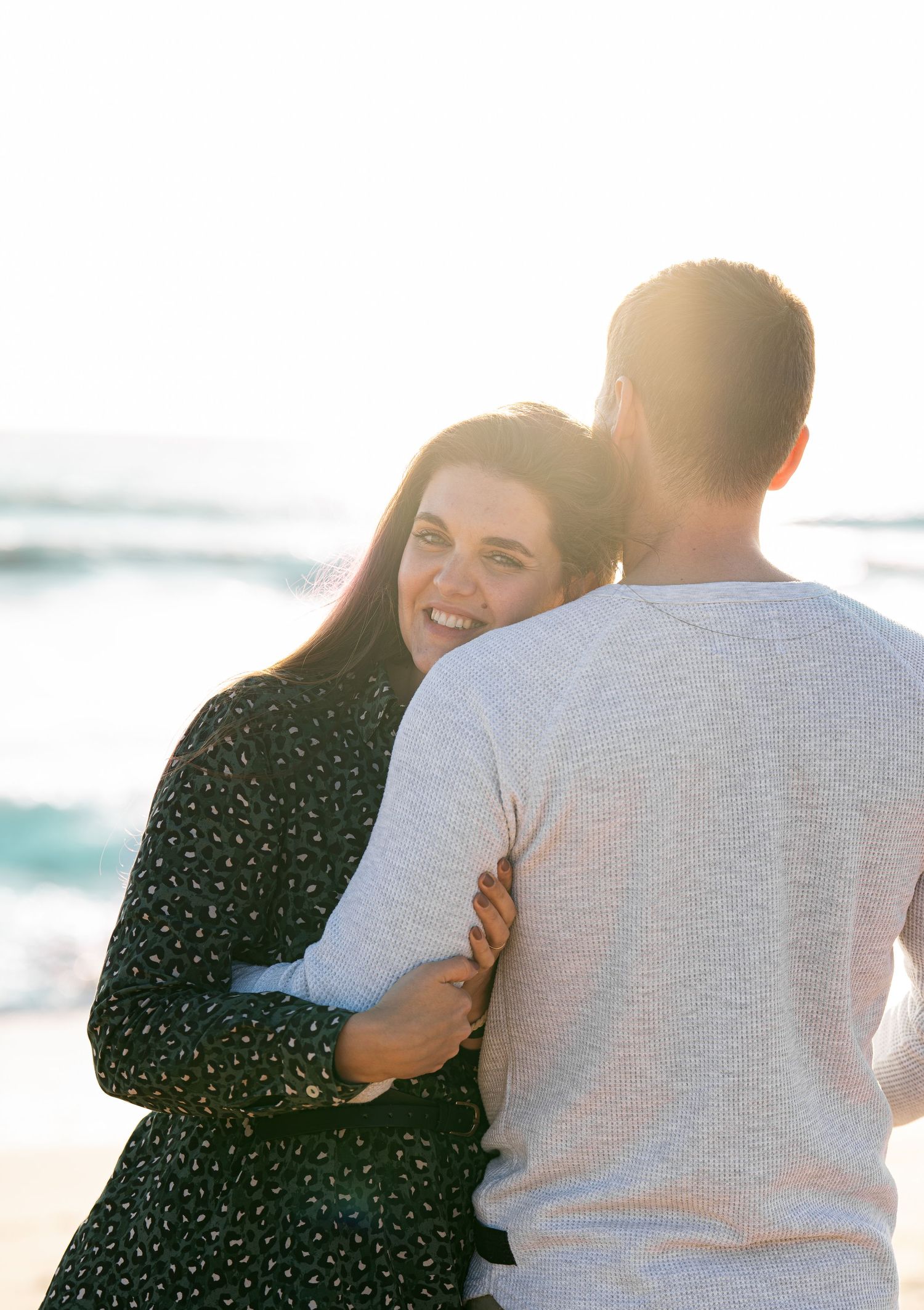 Candid moments of affection captured at sunset on a beach.