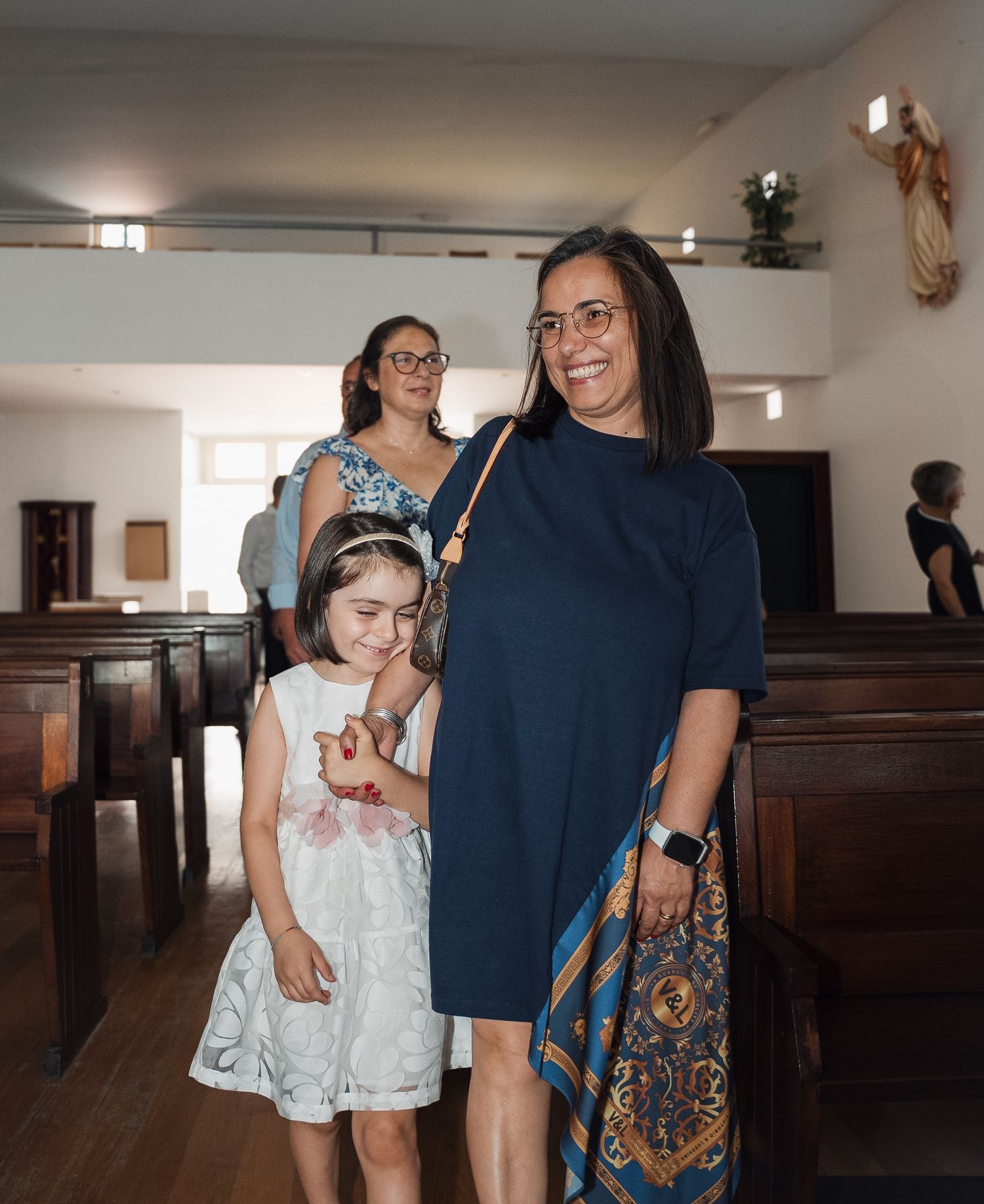 A group wearing white and navy blue gather in a church interior for a special occasion.