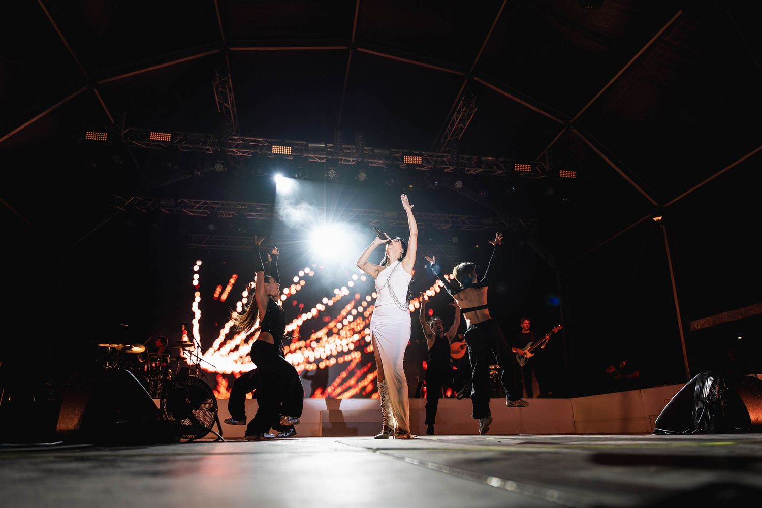 Dark stage with dramatic spotlights creating silhouettes during performance.