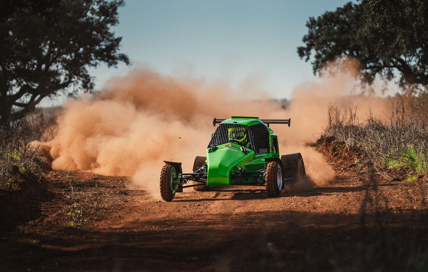 Bright green dune buggy racing through a dirt track creating dramatic dust clouds.