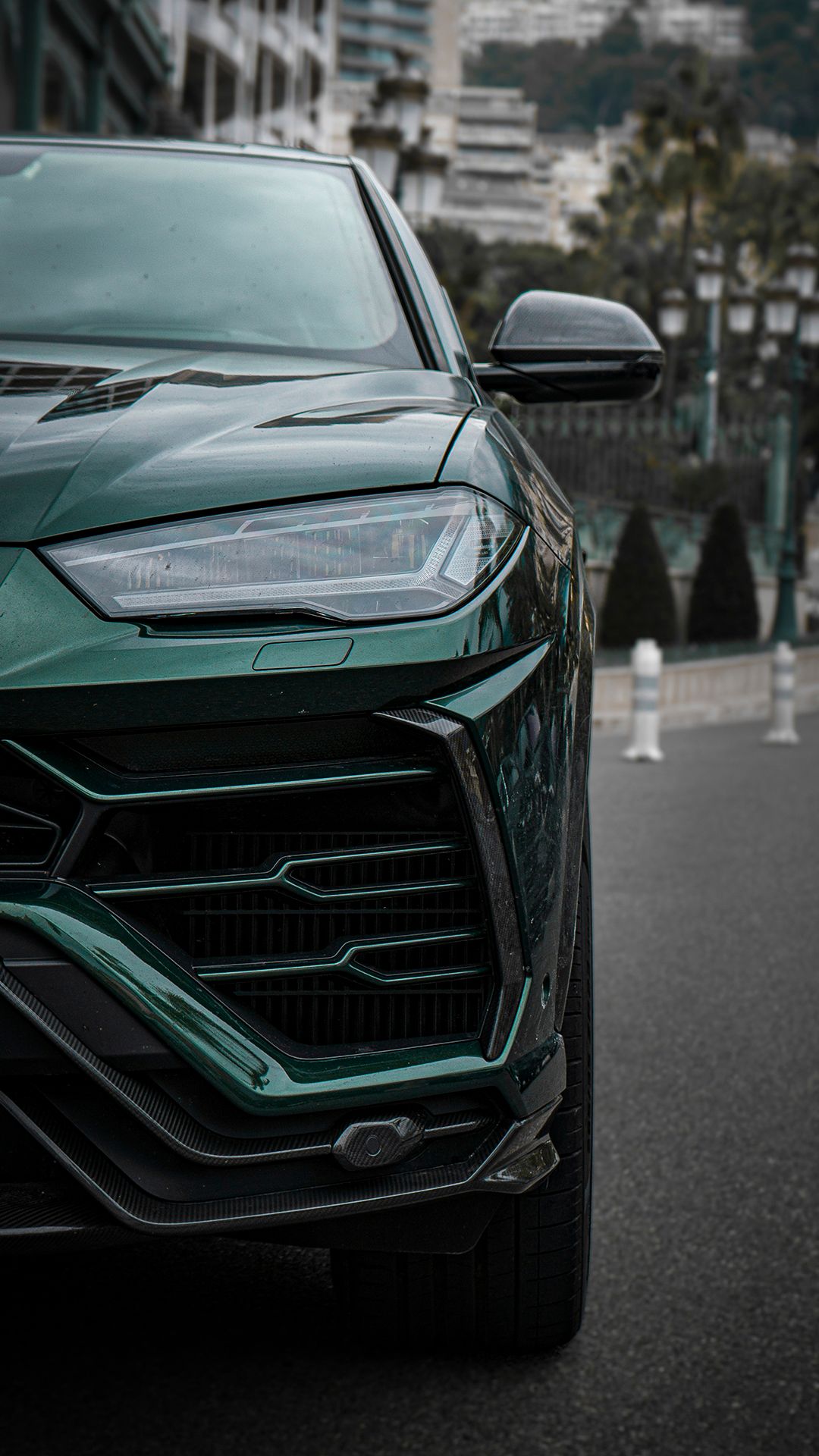 Front end detail shots of a dark green Lamborghini Urus SUV.