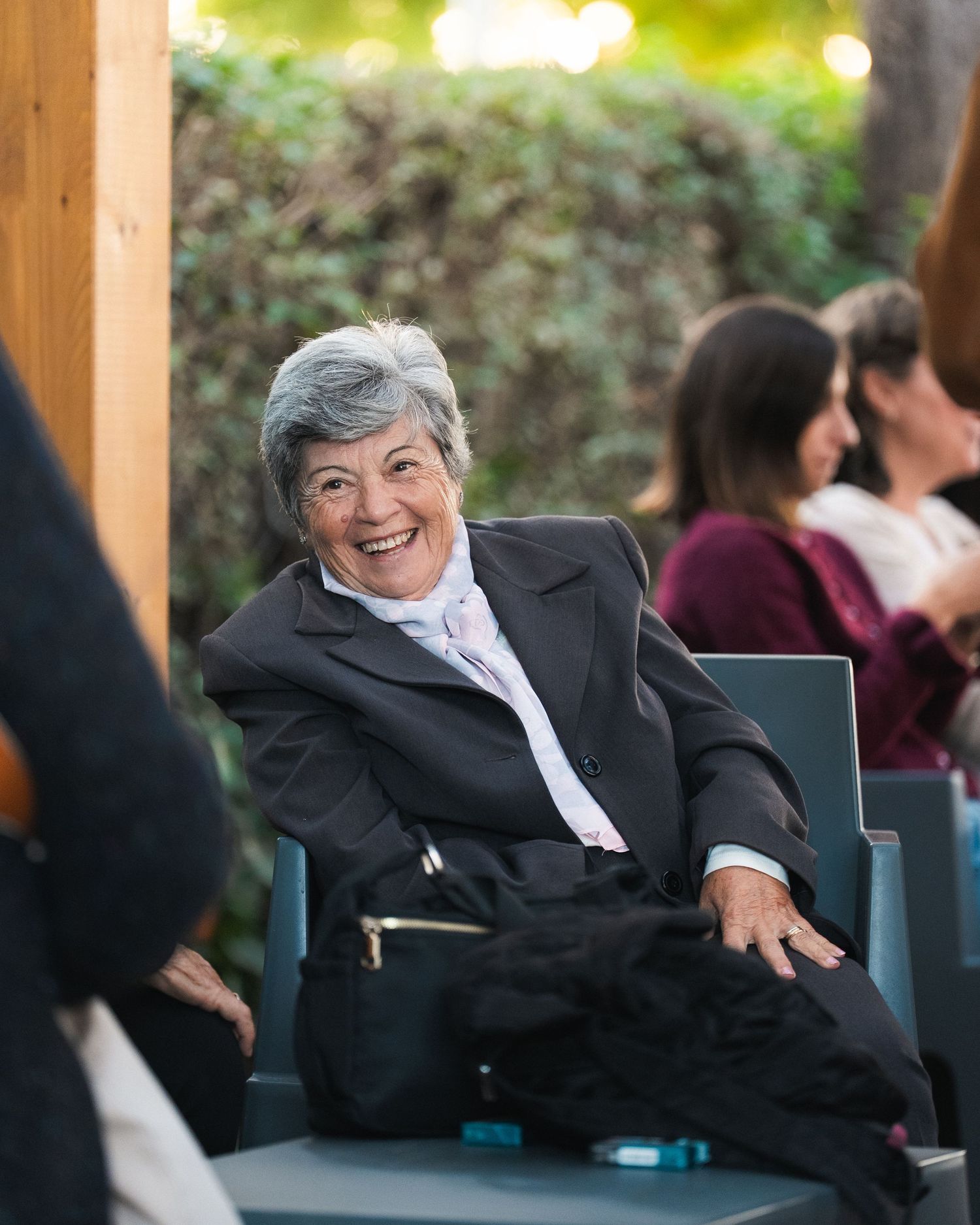 Person in formal attire relaxing in outdoor seating area with natural lighting.