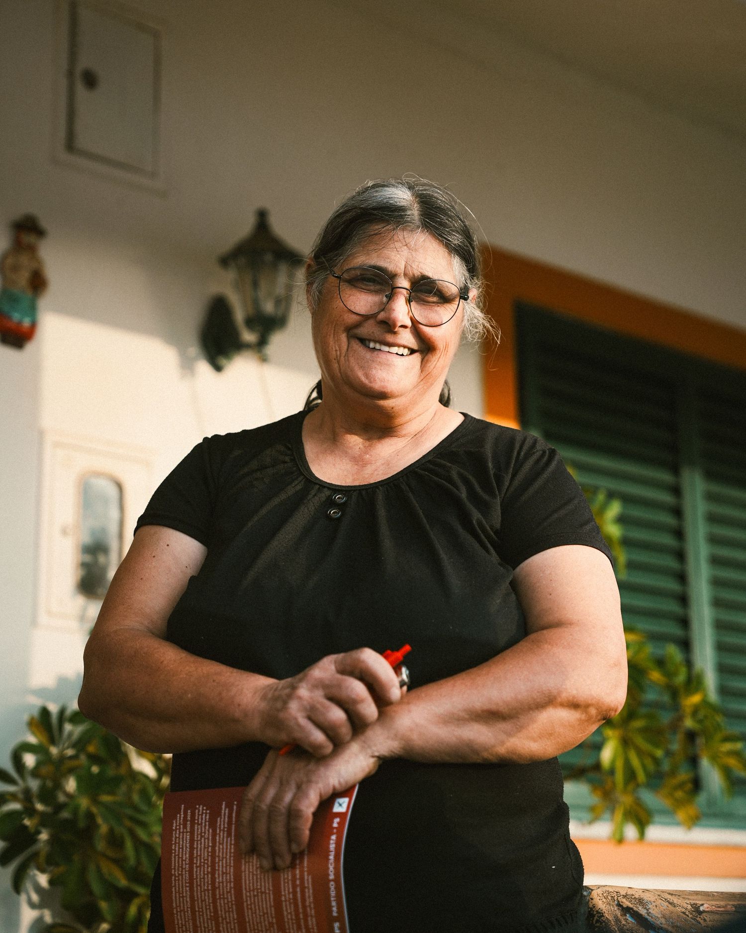 Person in black shirt leaning on wooden railing on front porch.