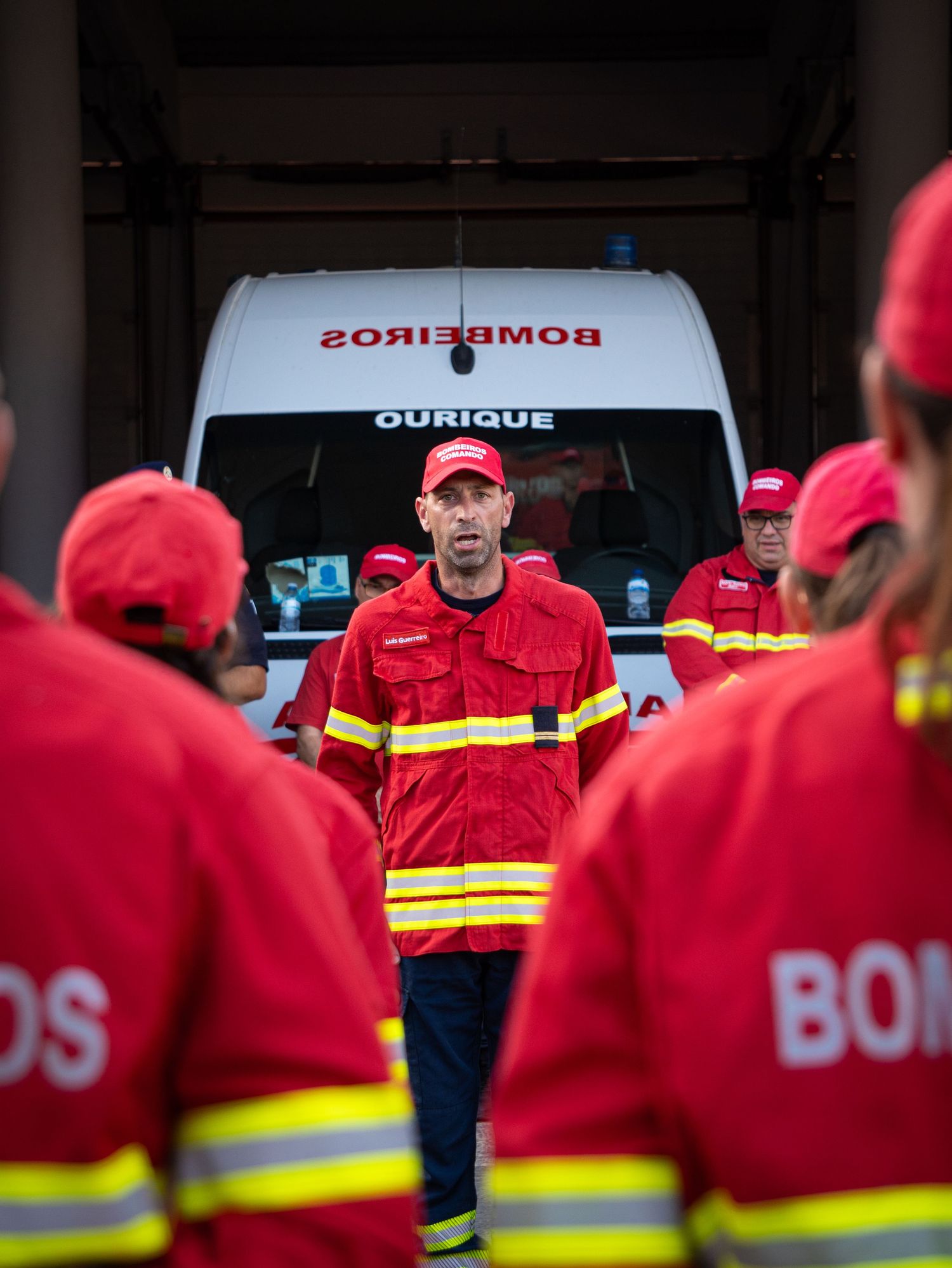 Fire department personnel in red uniforms assembled in front of emergency vehicles.
