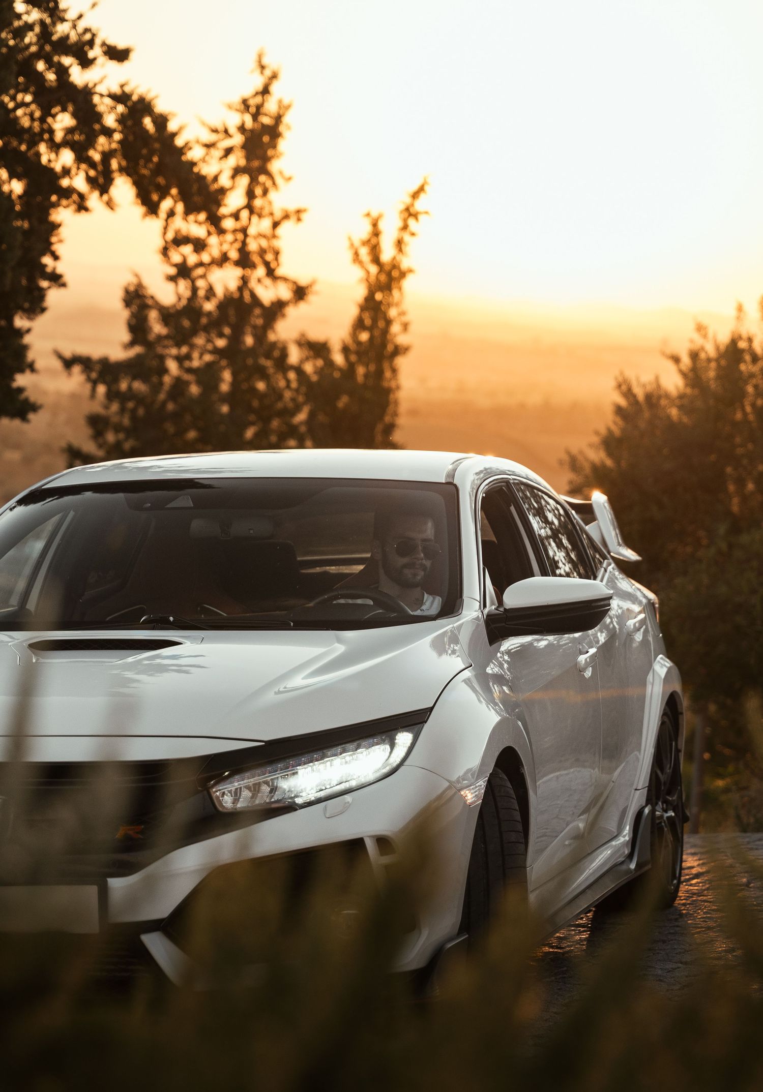 White sports car photographed at sunset with dramatic lighting and shadows.