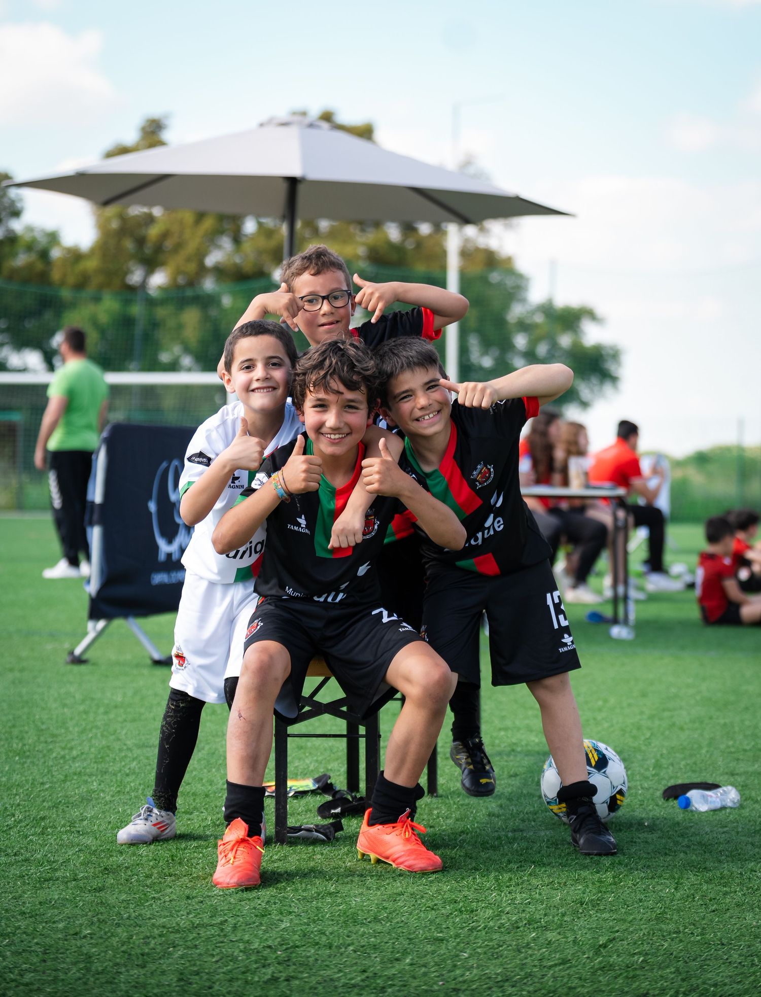 Youth soccer players resting on bench during break at outdoor sports field.