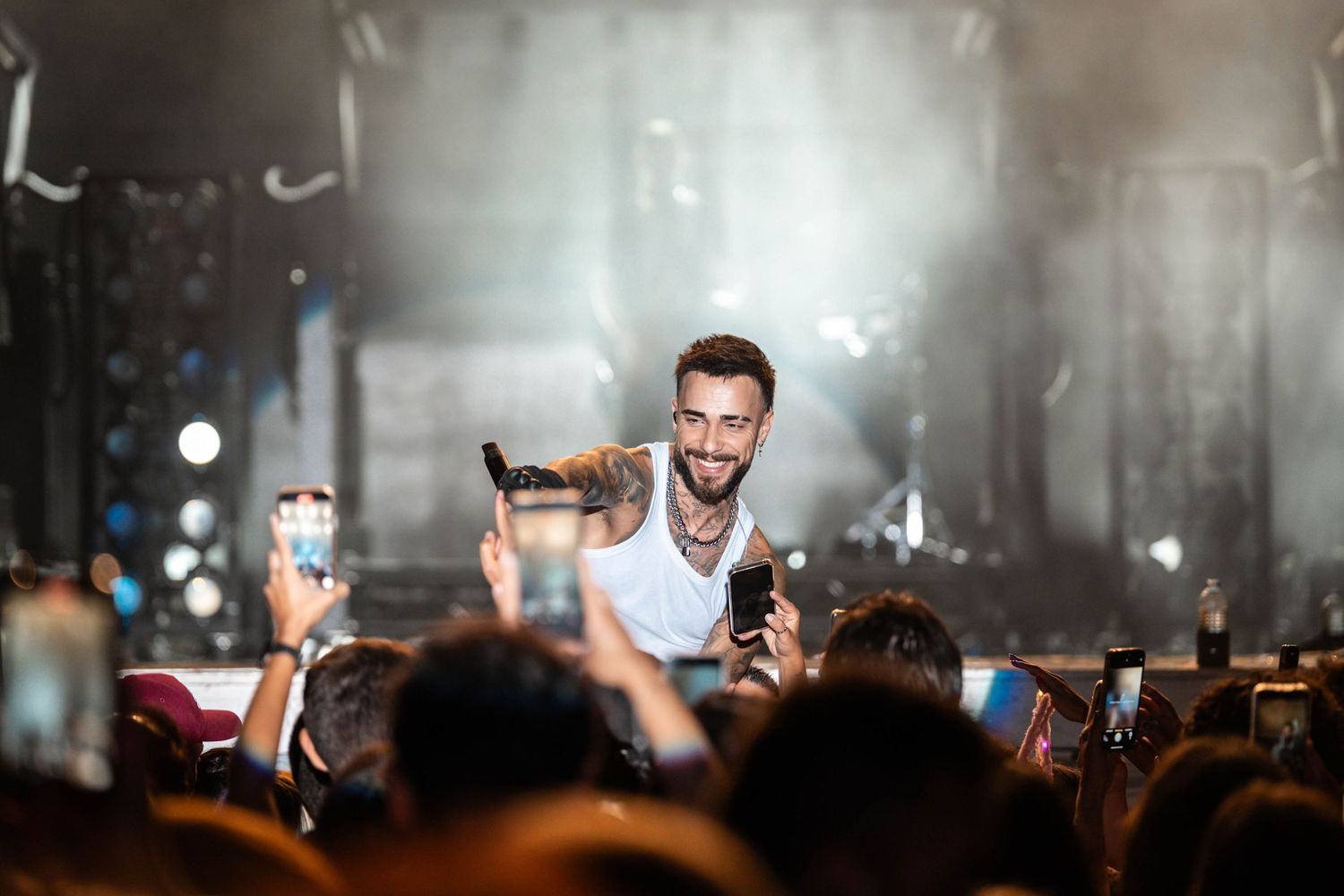 Stage performer engaging with enthusiastic crowd during nighttime concert performance.