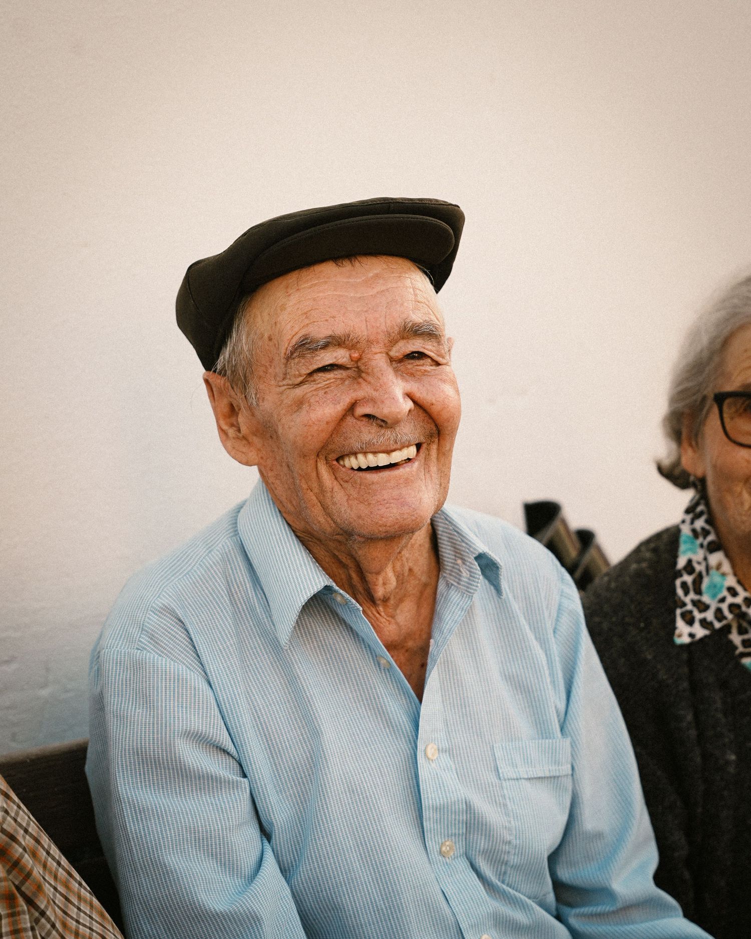 Elderly person in light blue shirt and cap smiling warmly in a series of candid shots.
