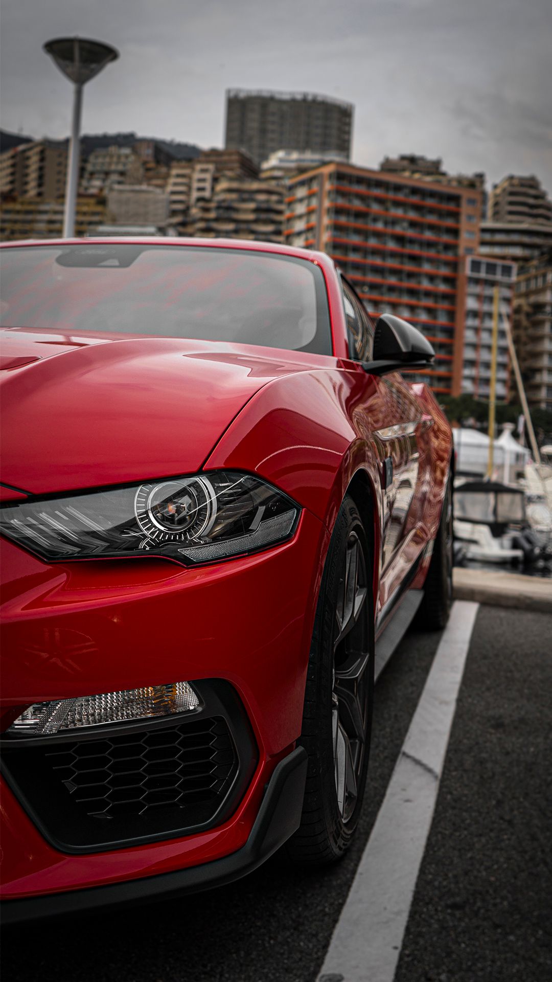 Front end details of a red sports car parked in an urban setting.