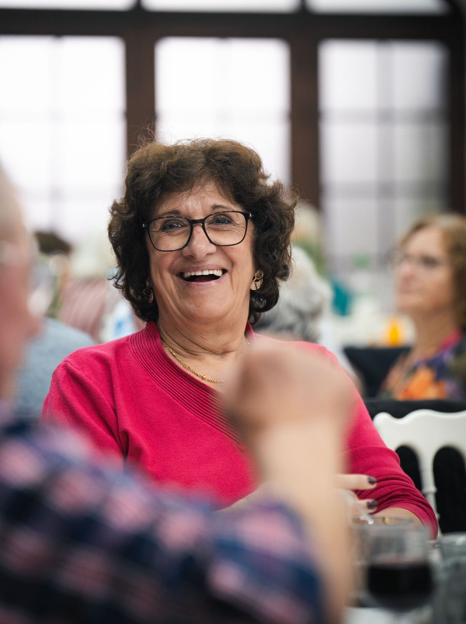 Person in bright red top sharing an enthusiastic laugh during a group event.