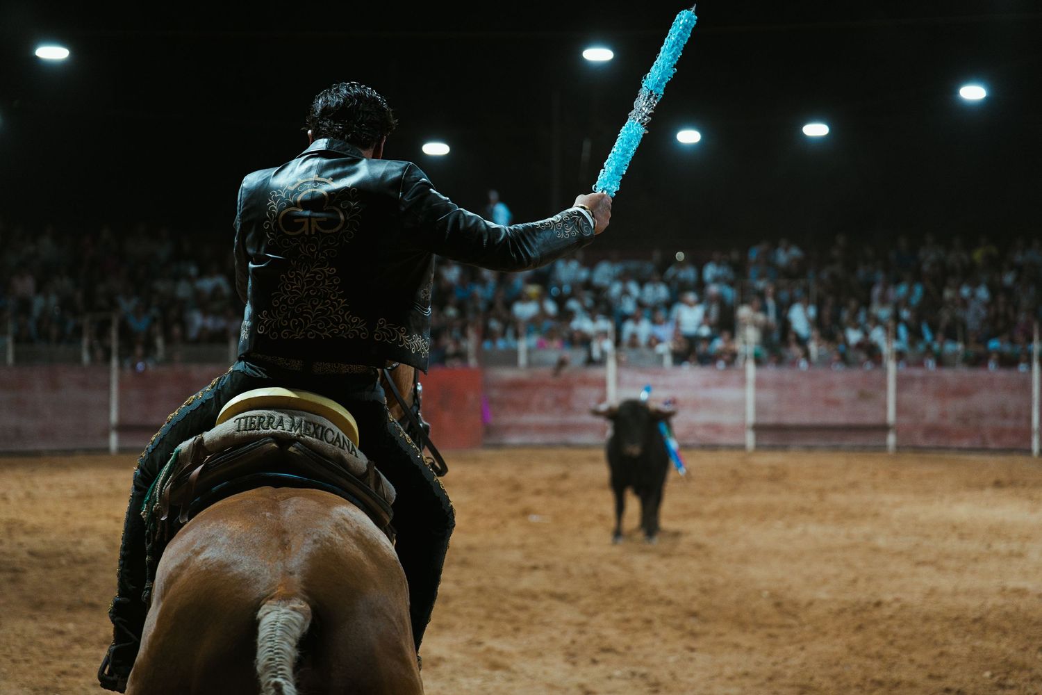 Rodeo performance under bright stadium lights with crowd in background.
