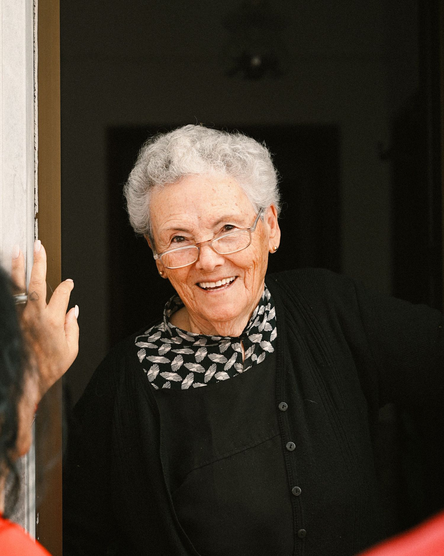 Person wearing black top and patterned scarf smiling warmly.