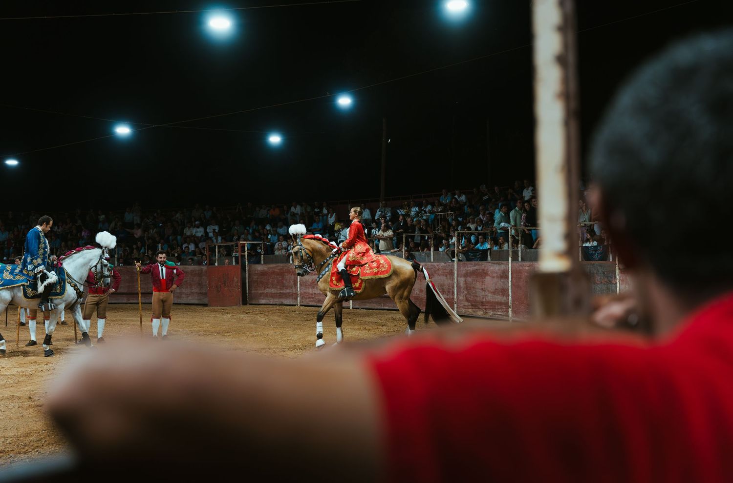 Soccer match under stadium floodlights with players competing for the ball during a nighttime game.