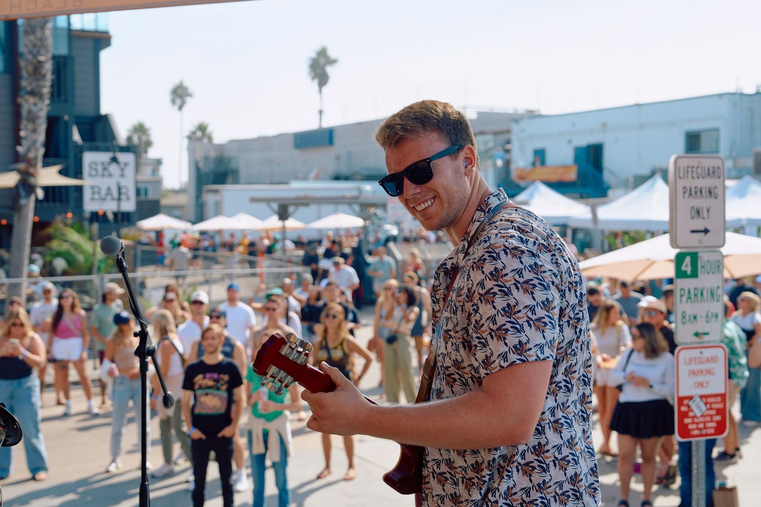 Musician playing guitar on an outdoor stage during daytime
