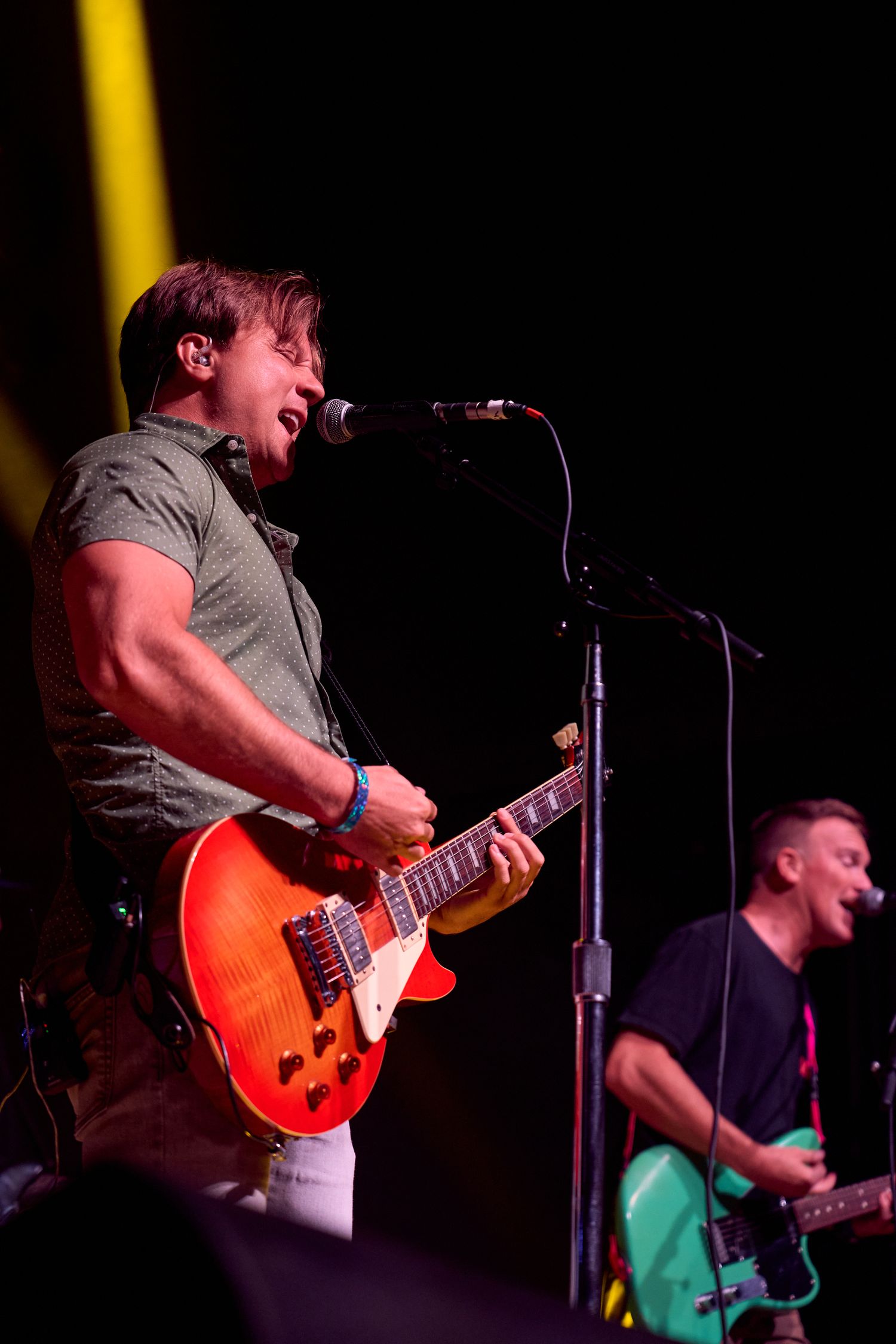Guitarists performing together on stage under concert lighting