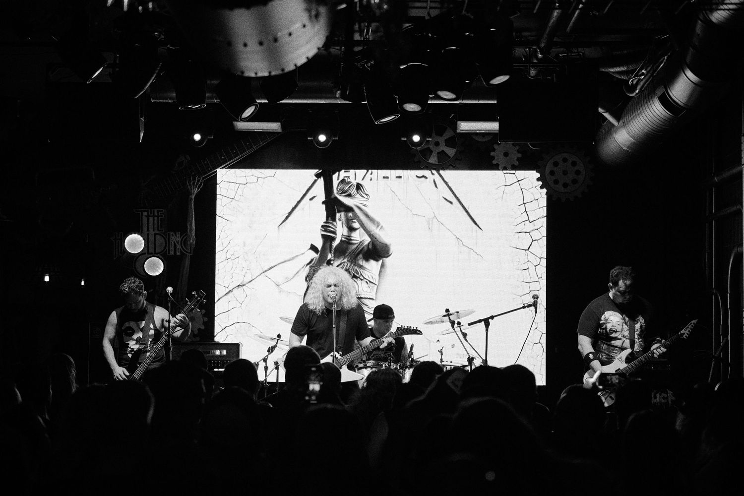 Black and white wide shot of band performing on stage in front of a crowd
