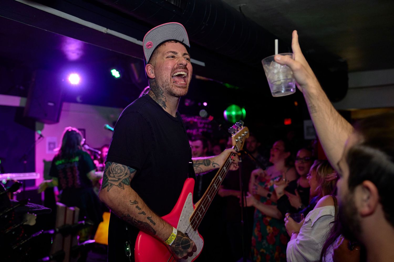Bass player performing on stage with crowd reaching toward him