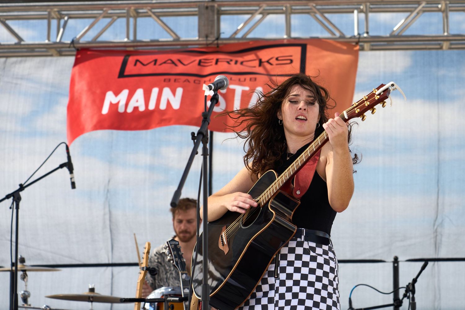 Singer playing guitar on an outdoor festival stage