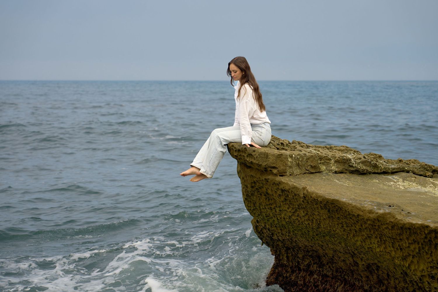 Portrait of woman sitting on a cliff overlooking the ocean