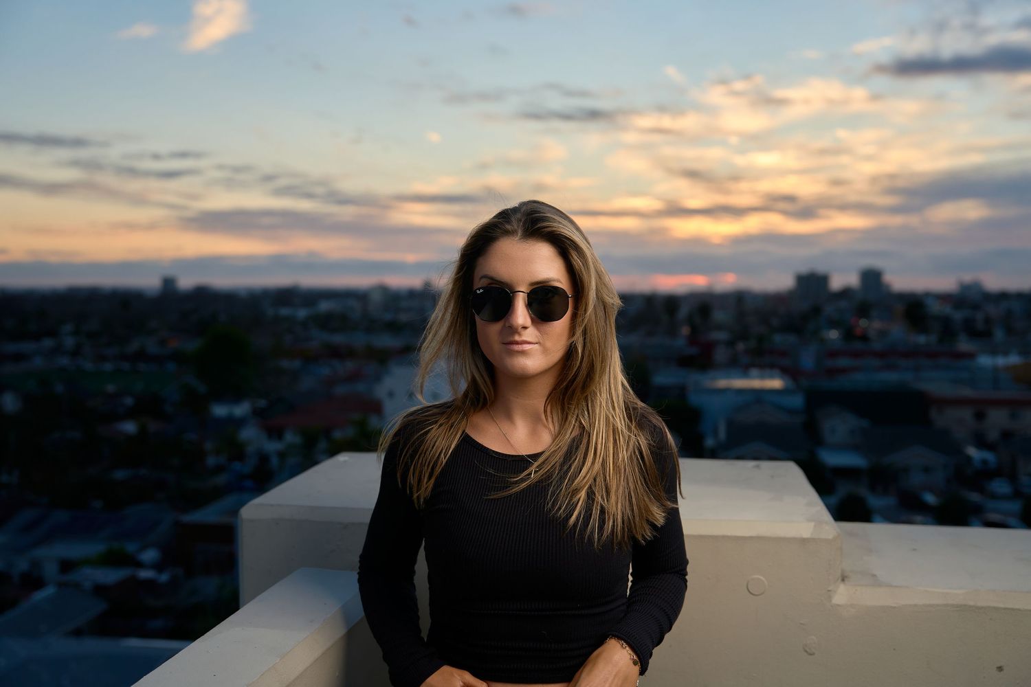 Portrait of woman smiling on a rooftop terrace at sunset