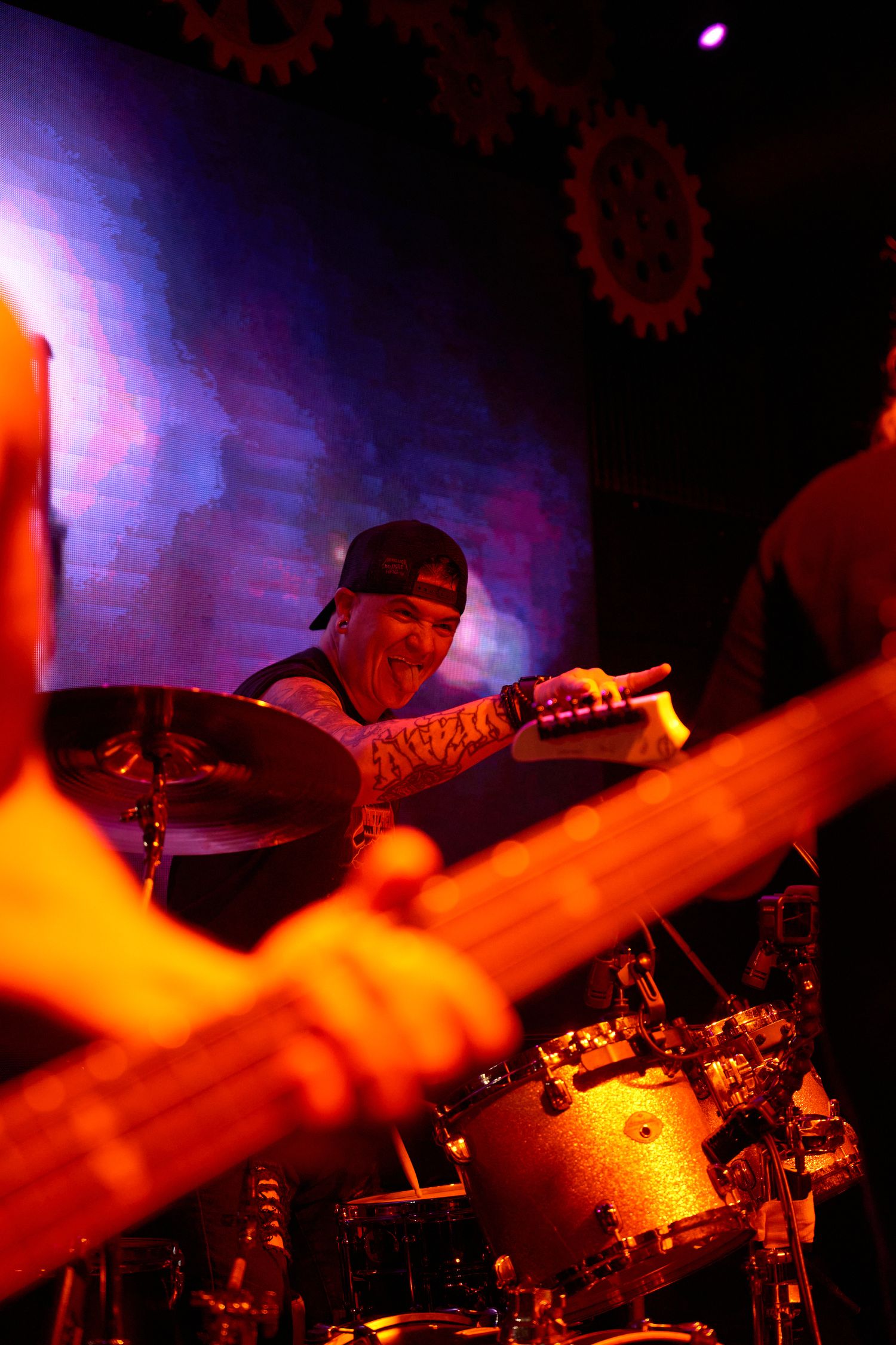 Close-up of drummer playing during a live performance under warm stage lighting