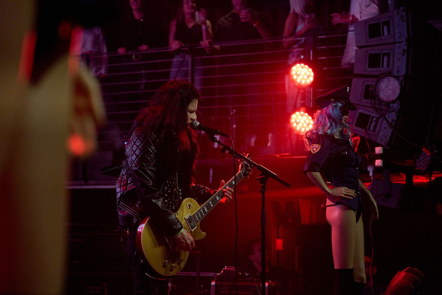 Guitarist performing on stage under red concert lighting