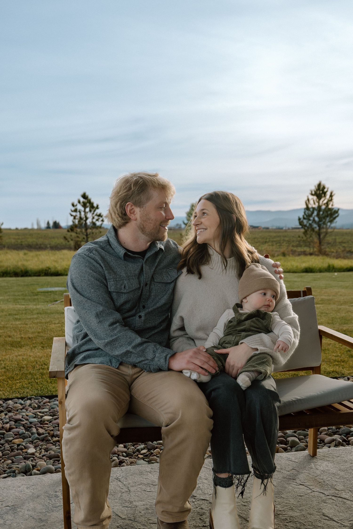 Couple sharing intimate laughs while sitting together on outdoor bench with desert landscape in background.