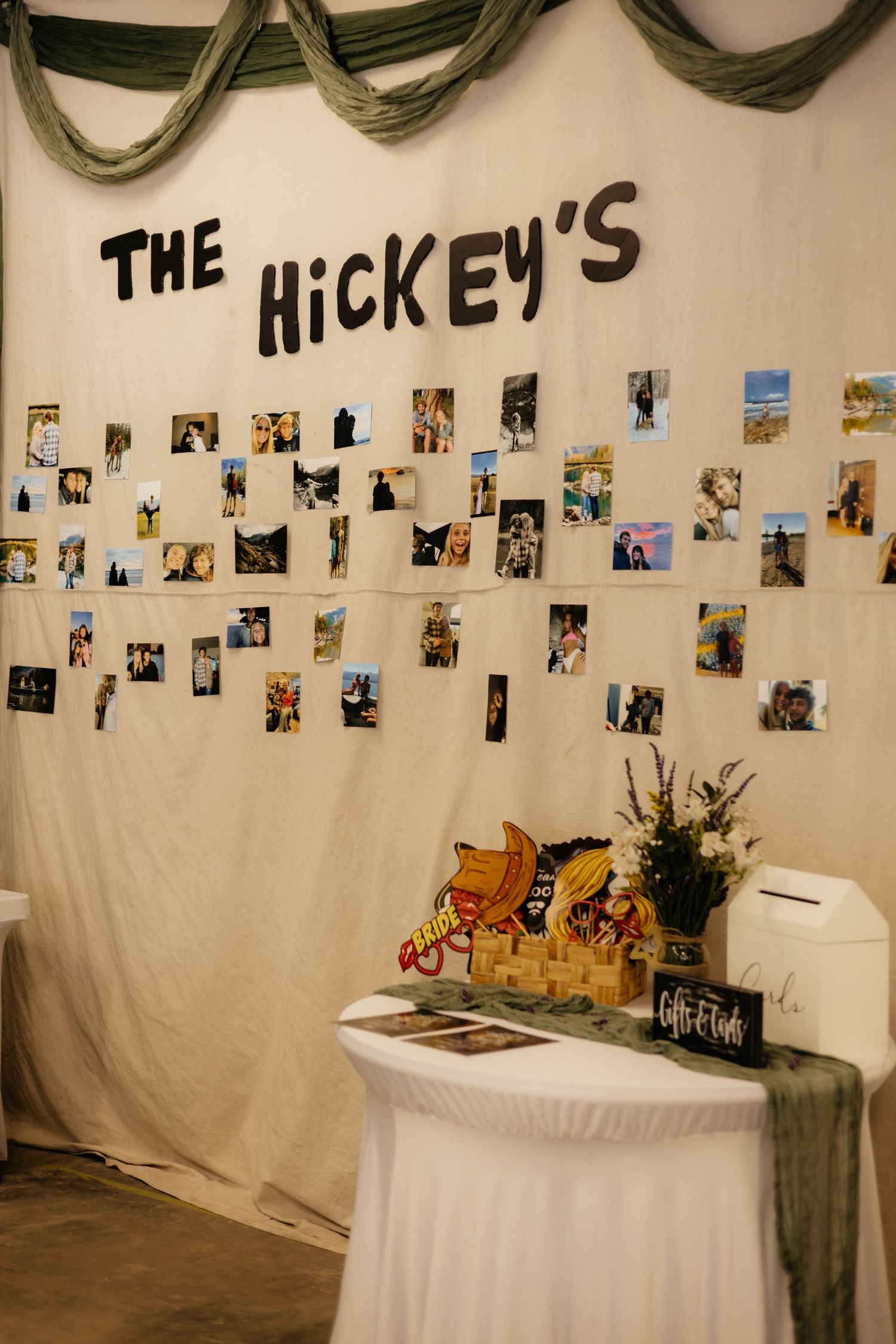 A rustic photo display with multiple pictures hung on strings against a white backdrop with decorative elements.