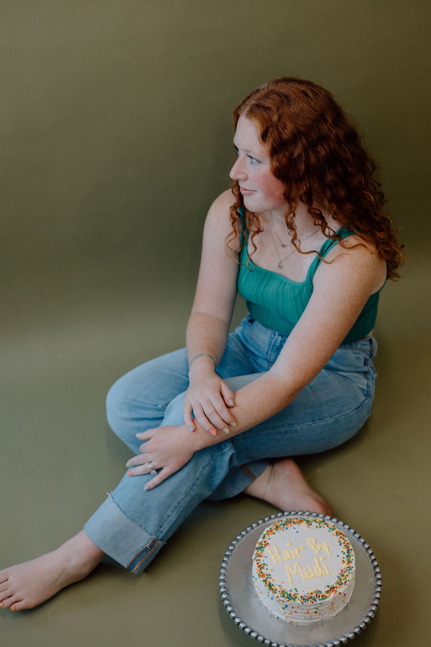 A casual portrait session featuring denim overalls and a decorated birthday cake on a plate.