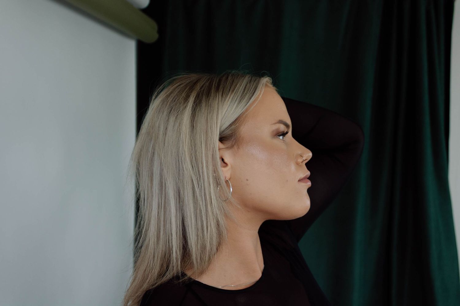 Profile portrait showing elegant pose against dark backdrop.
