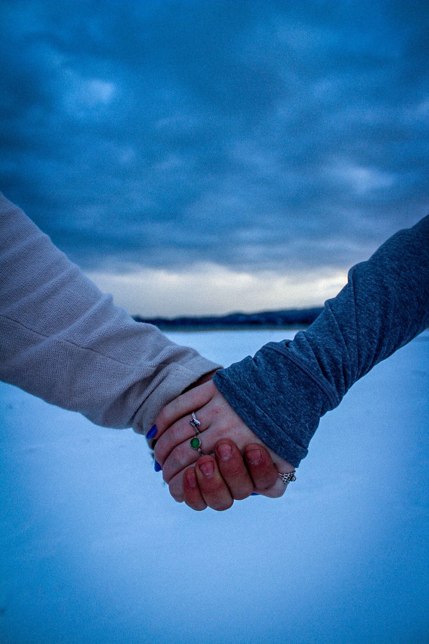 Two people holding hands against a moody blue sky background captured in a sequence of progressive movement.