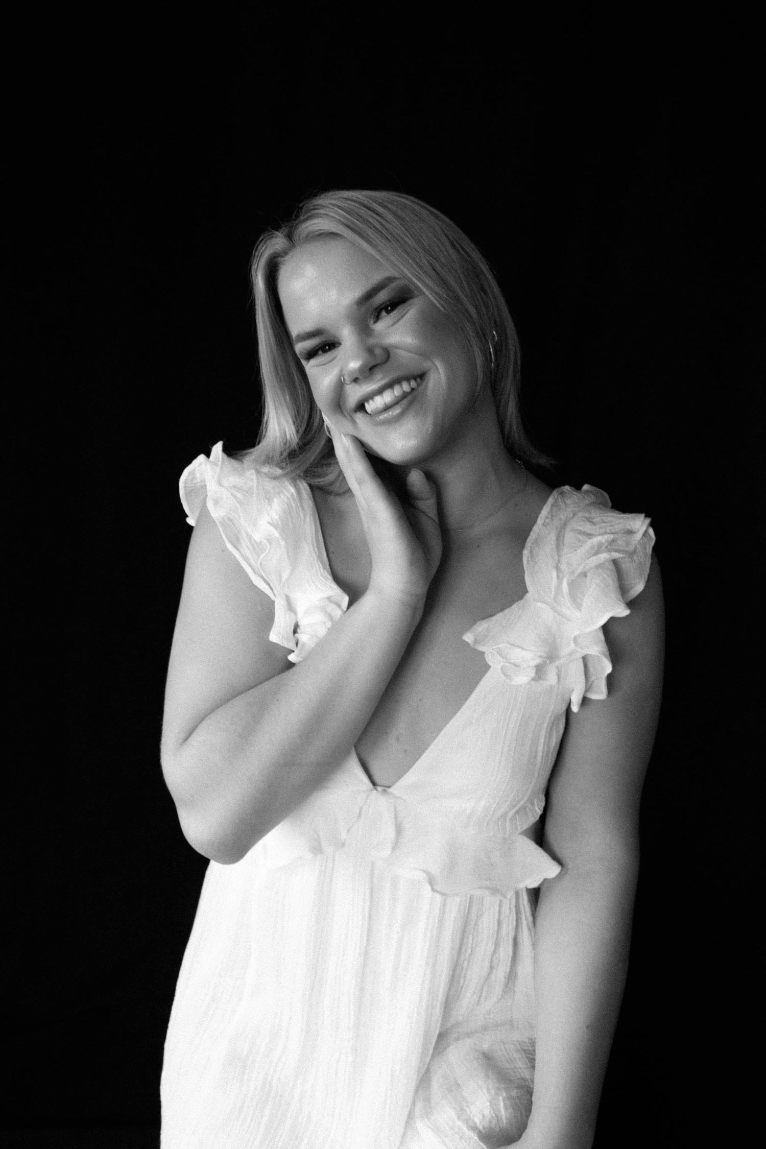 Ethereal portrait in white ruffled dress against dark background.