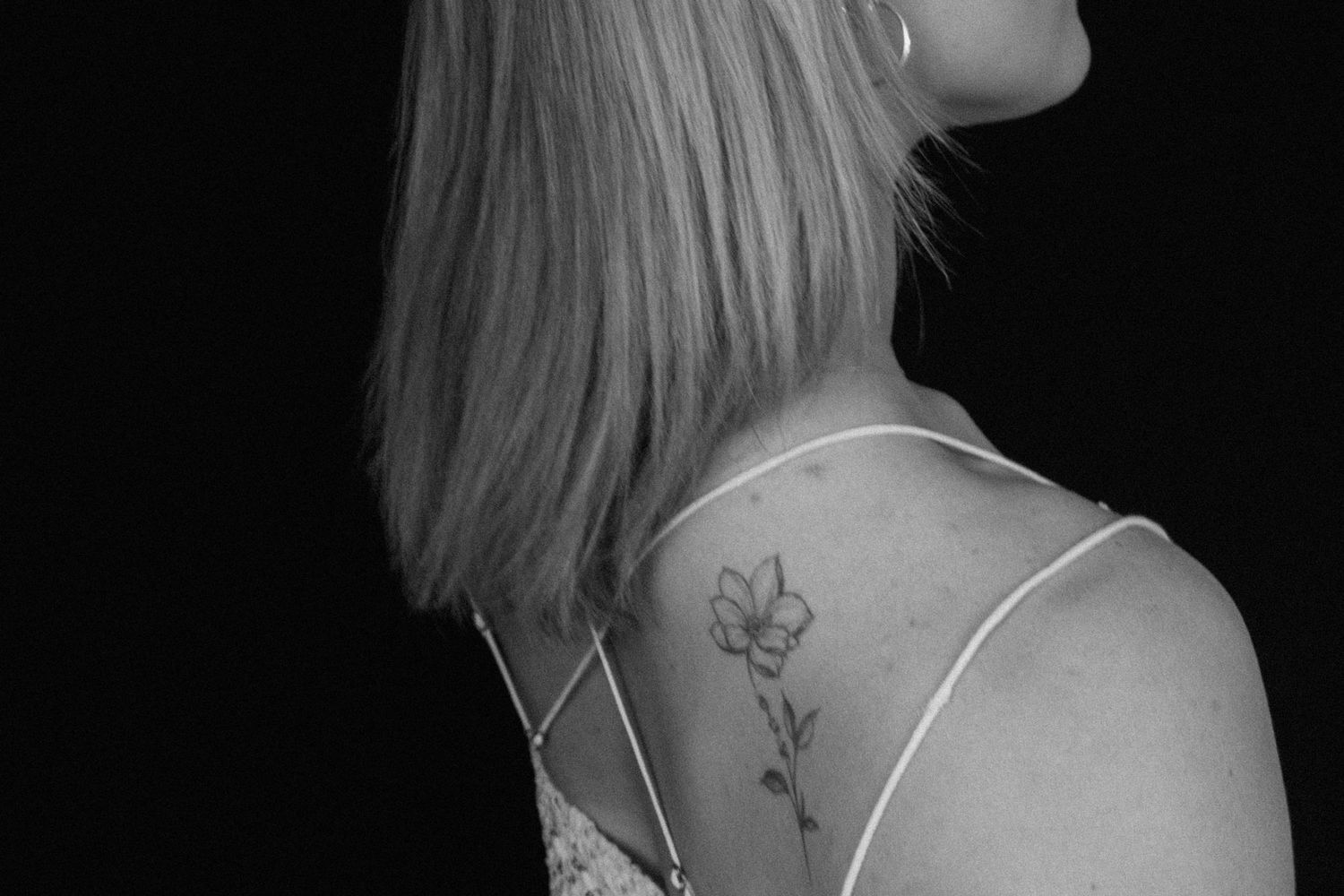 Black and white photo series showing close-up details of tattoos and body art on someone's neck and shoulders.