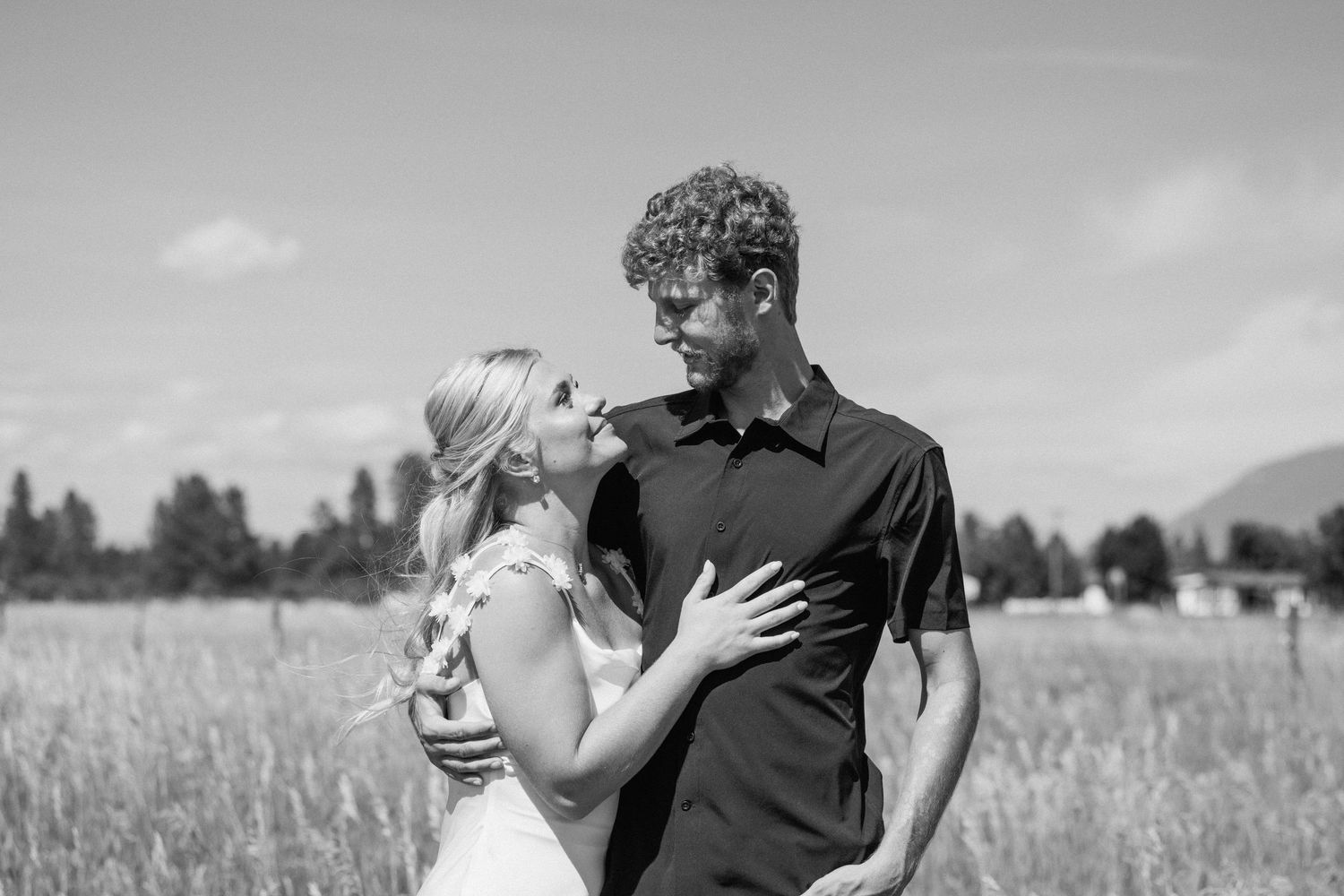 A romantic scene captured in black and white in an outdoor field setting.