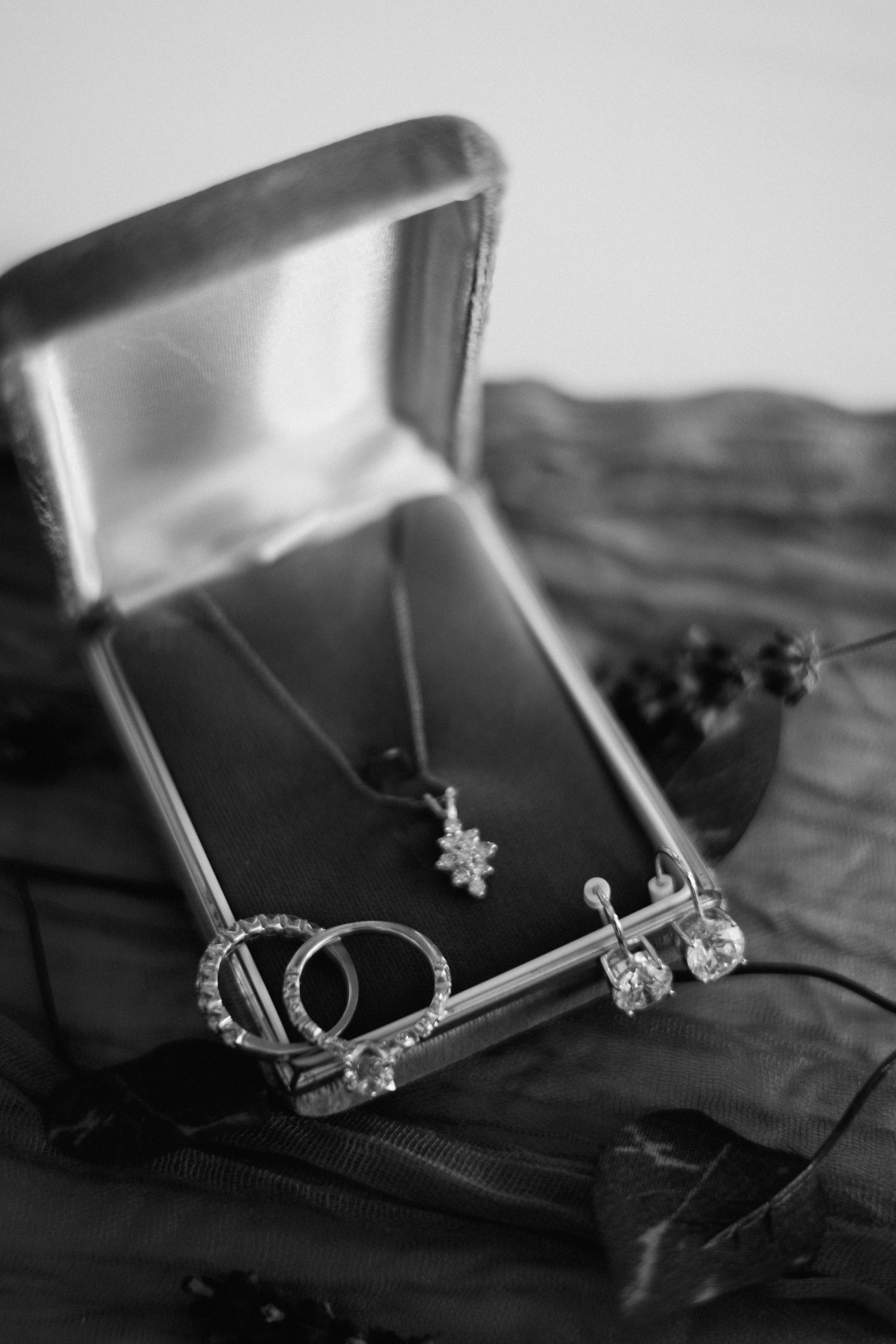 Detailed black and white photo series of delicate jewelry pieces laid out on a dark surface.