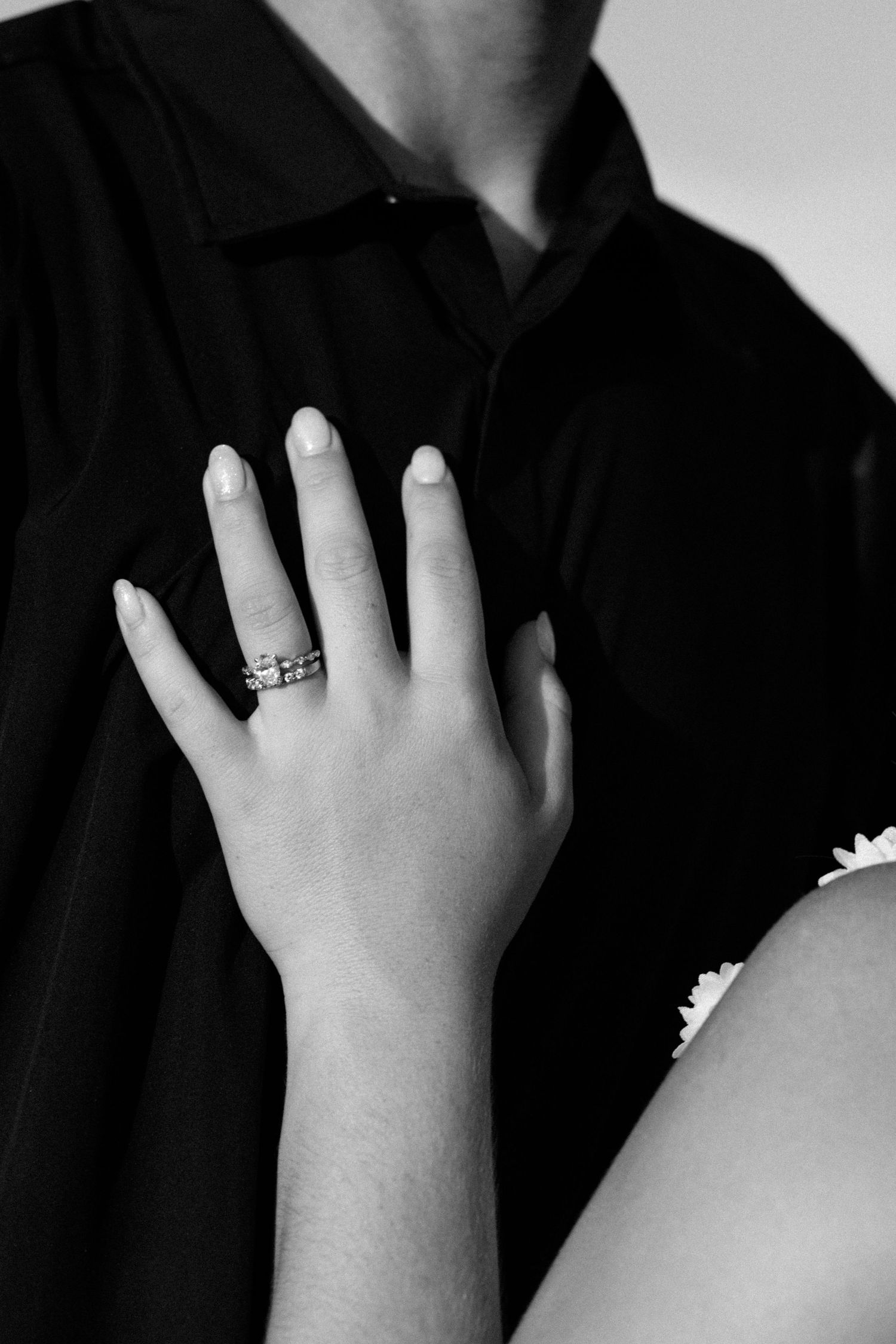 Black and white close-up sequence of hands with engagement ring against dark clothing.