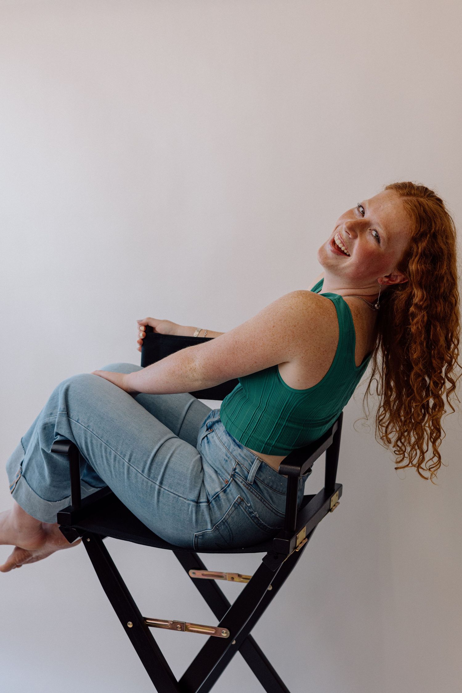 Sequence showing person in green top reclining dramatically on director's chair against white background.