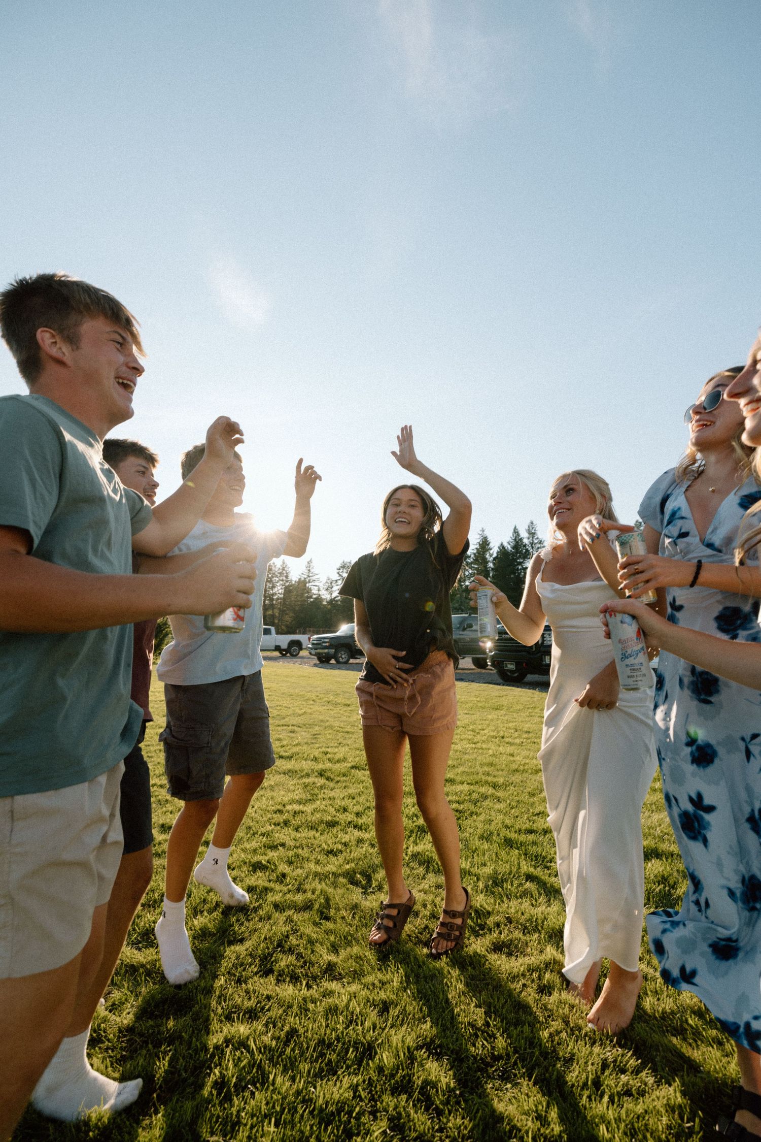 Group of people celebrating outdoors on a sunny grassy hill.