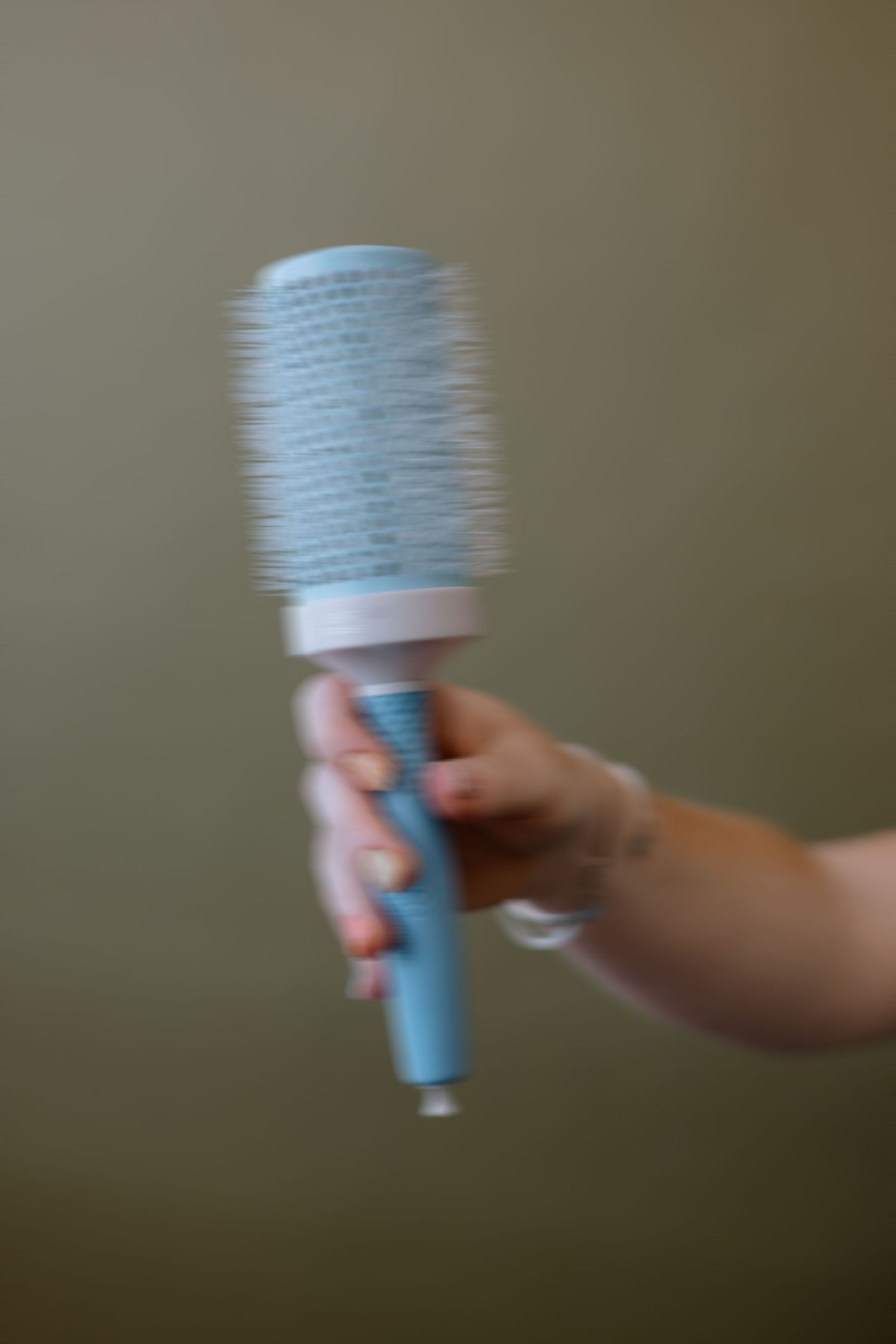 Motion blur sequence shows a hand moving a light blue drinking cup against a blurred background.
