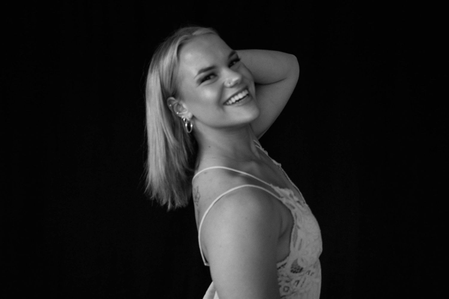 A series of black and white portrait photos showing a person posing in different angles with joyful expressions.