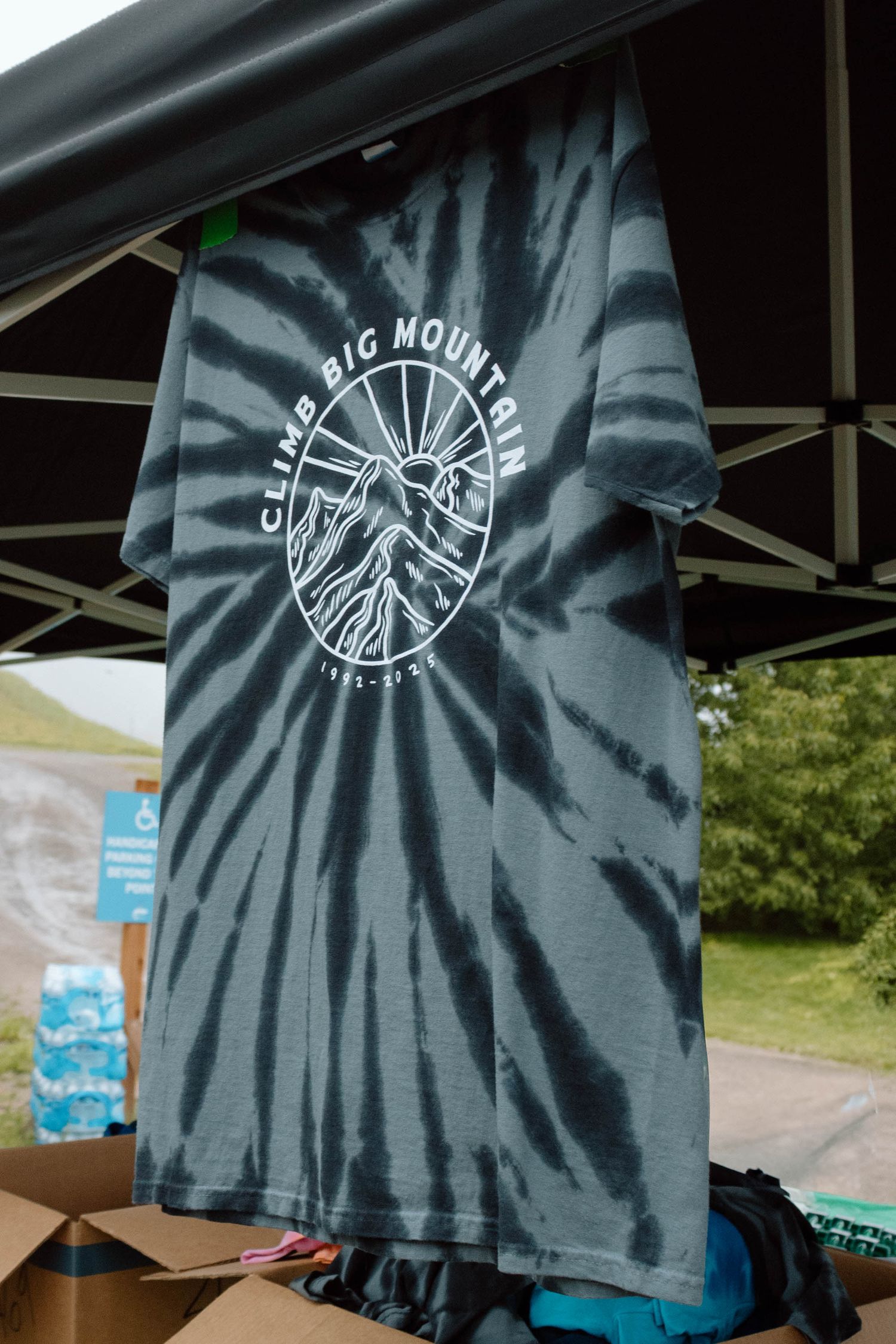 Black t-shirt with Big Mountain logo displayed on outdoor event stand.