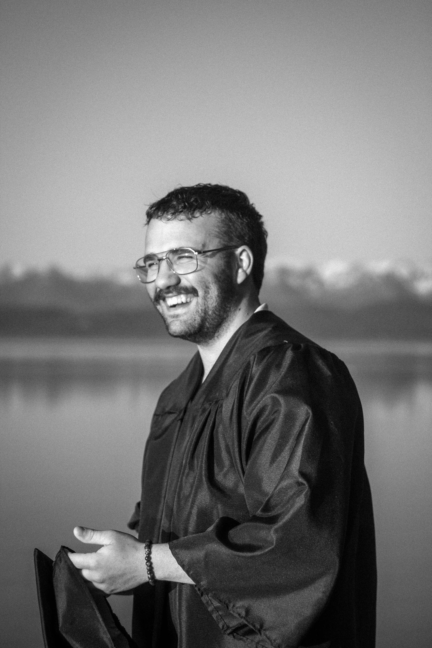 A series of black and white portraits showing someone in dark clothing smiling against a blurred background.