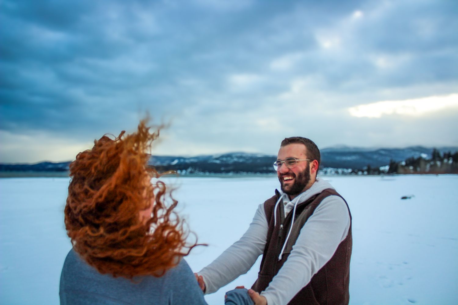 Happy pair takes playful photos together in snowy outdoor winter setting.