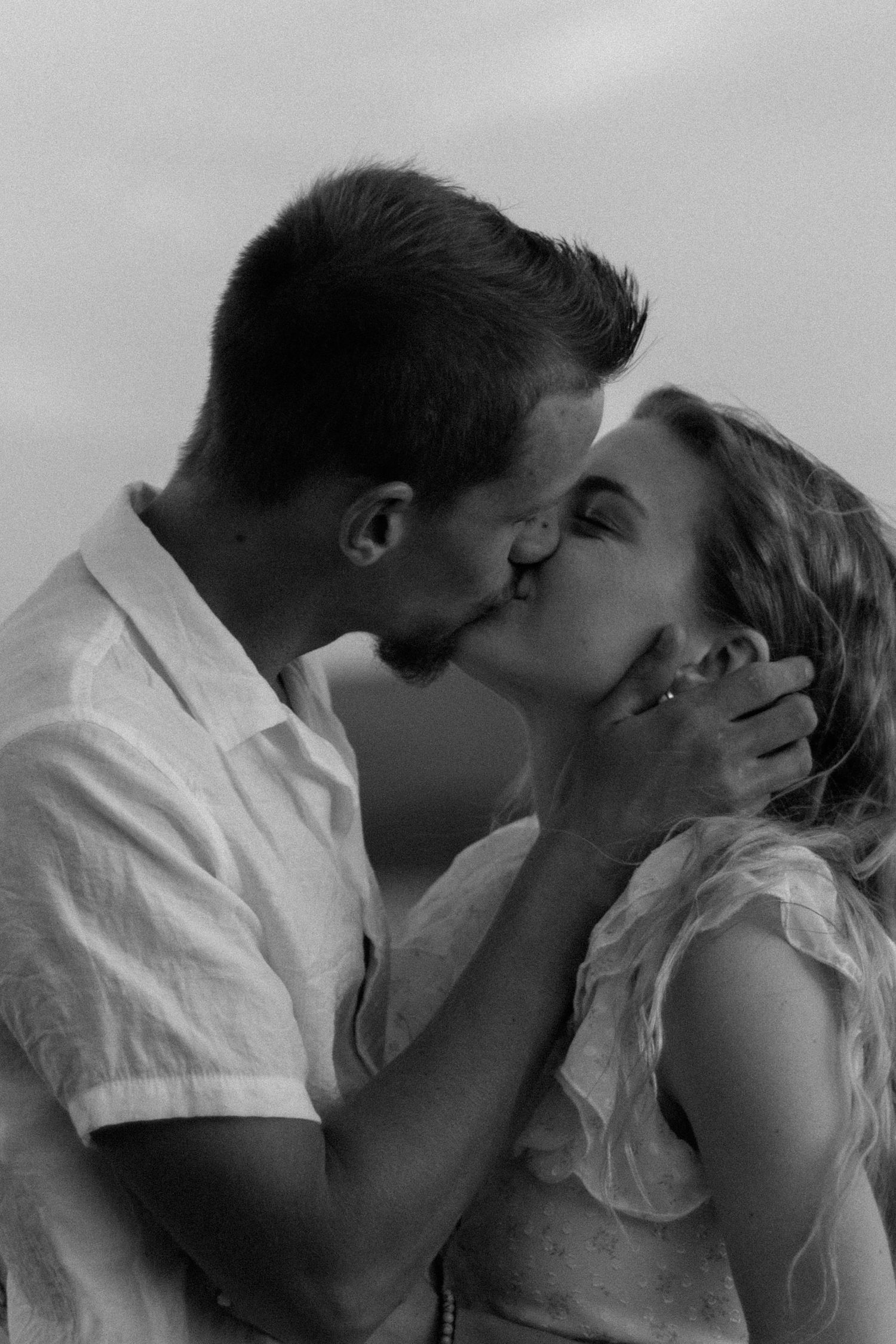 Black and white romantic sequence showing a tender kiss between two people in white clothing.