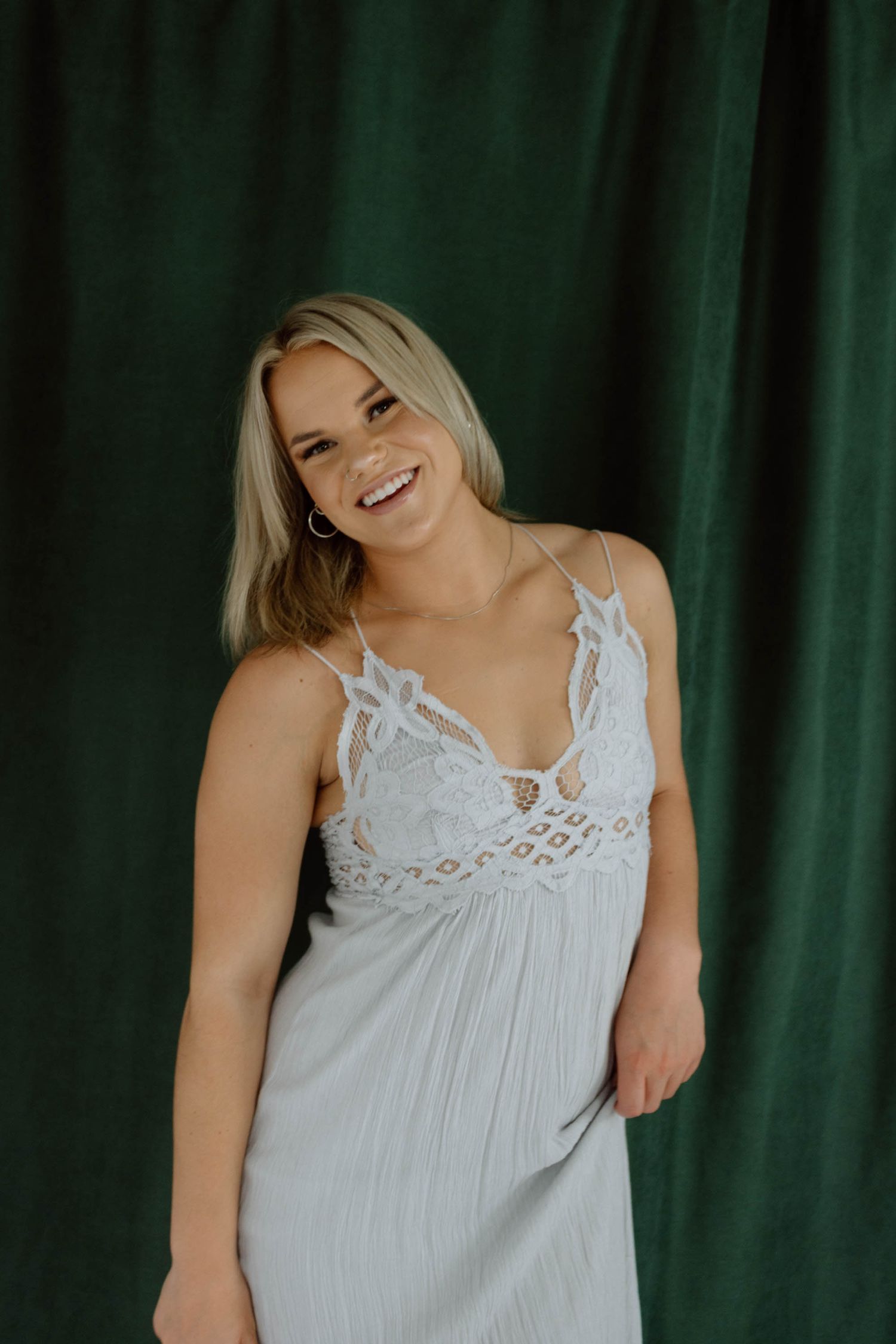 Four sequential photos show someone in a white lace-trimmed top laughing and expressing joy against a dark green backdrop.