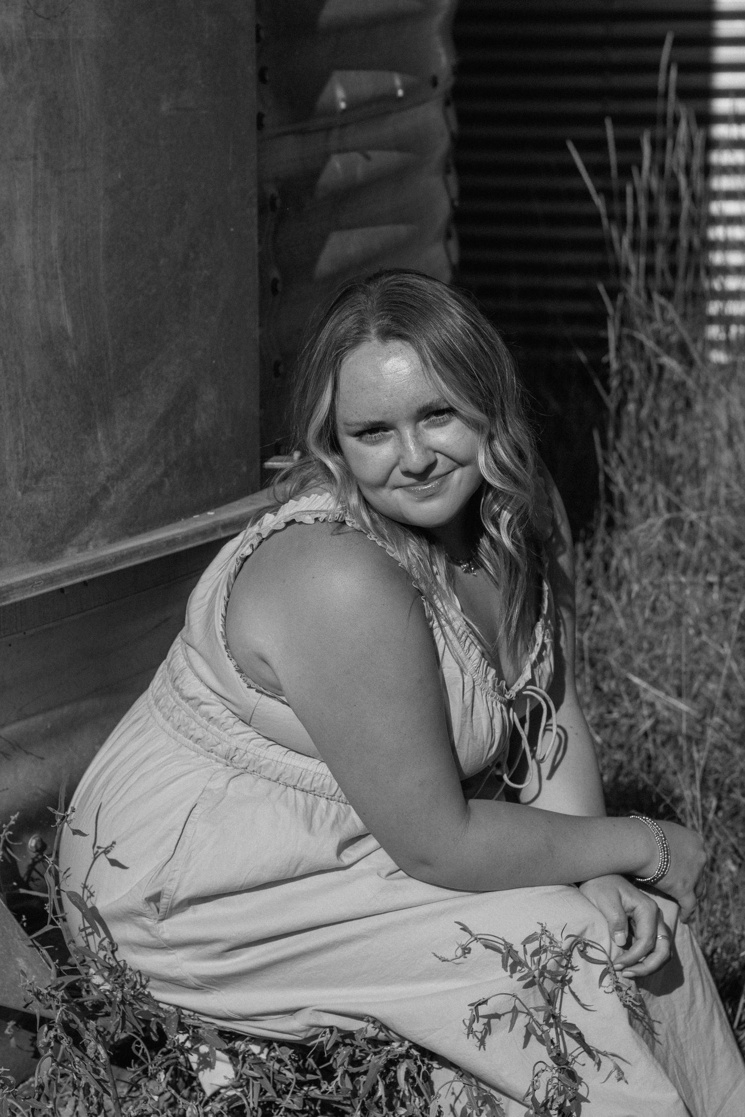 A black and white portrait photo of someone reclining on a couch wearing a light-colored dress.