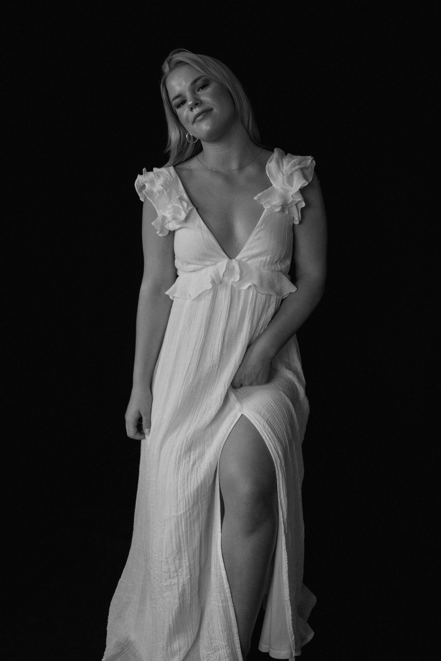 A series of black and white photographs showing a white ruffled dress against a dark background.