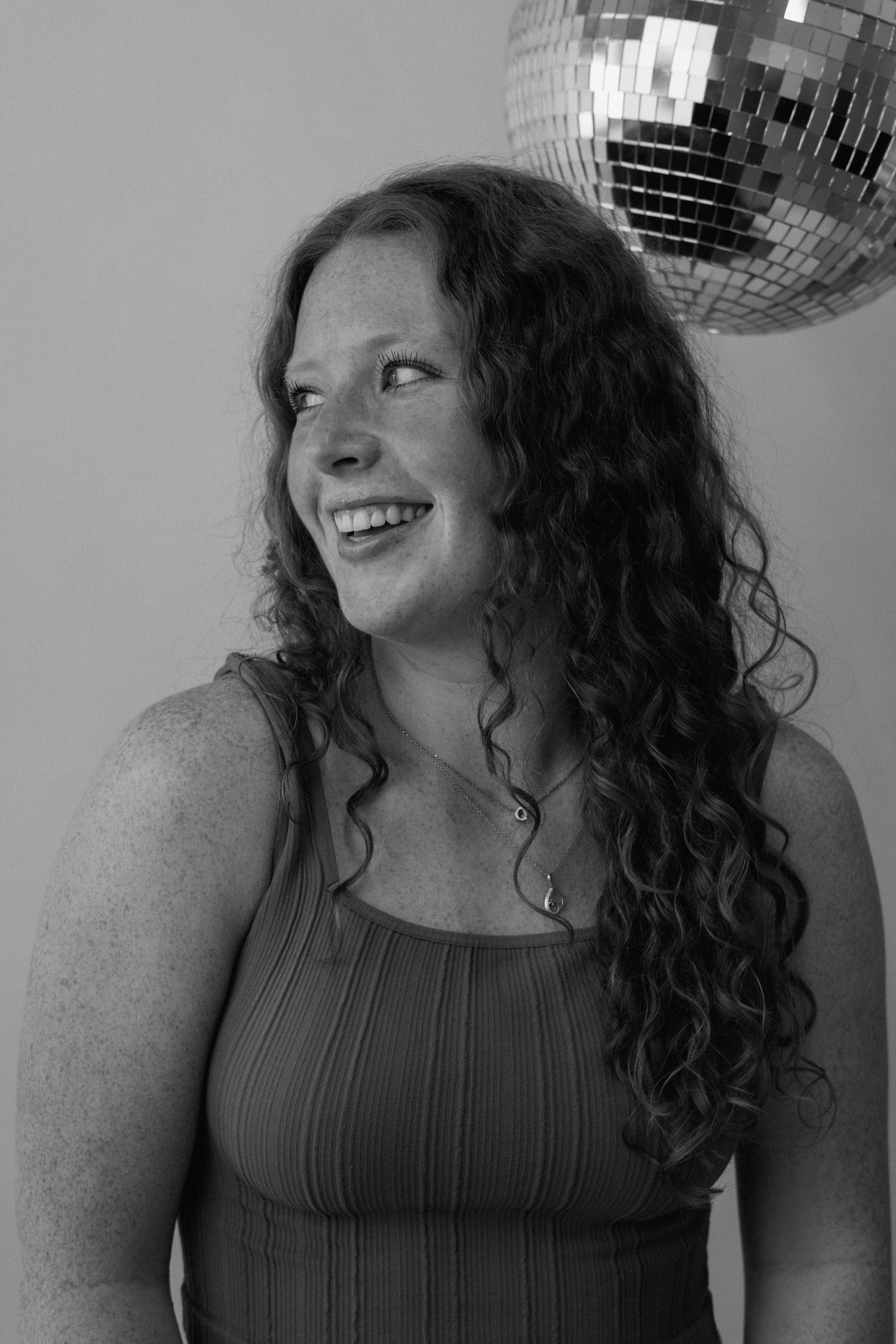 Person posing with disco ball in black and white portrait series.
