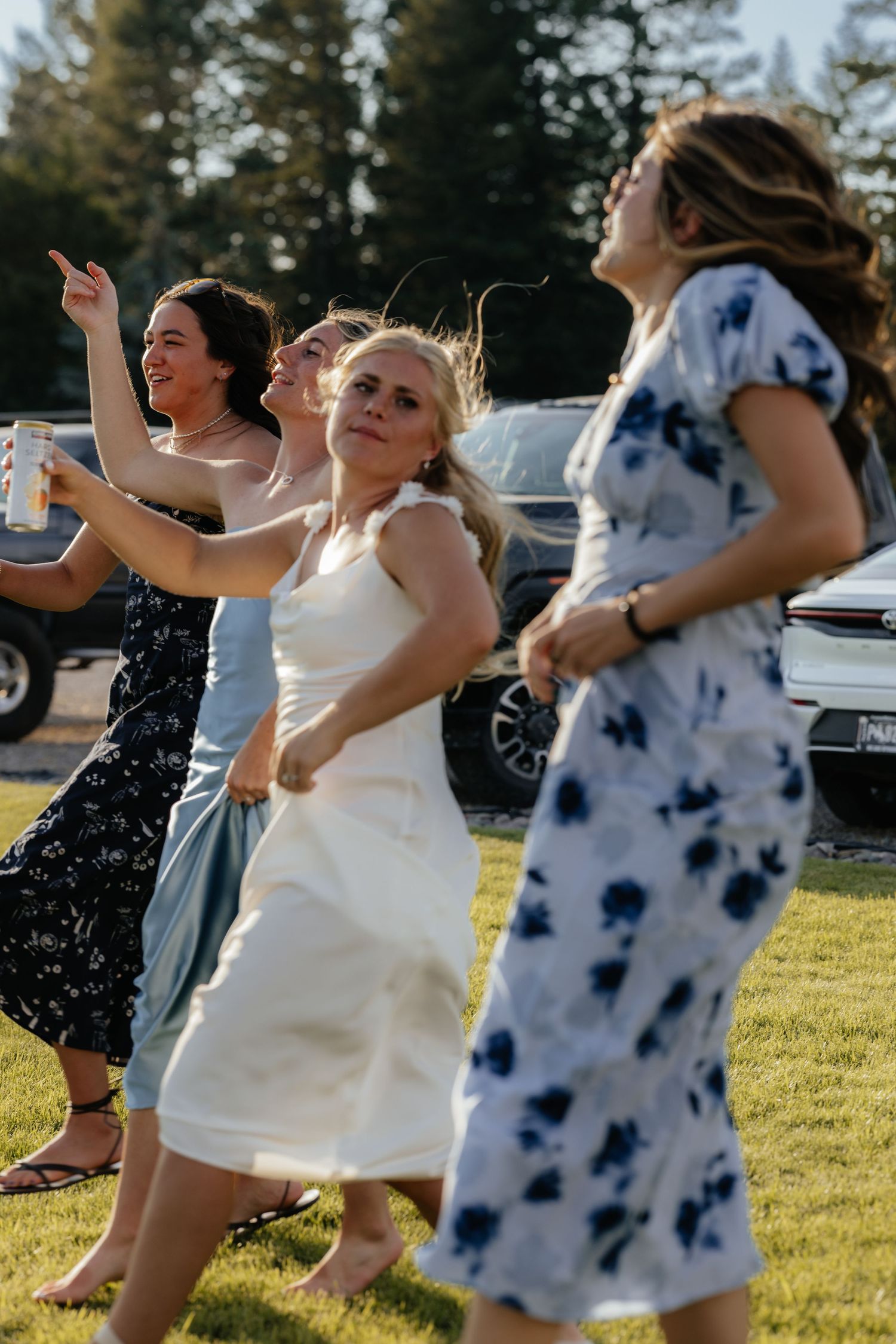 Group dancing and celebrating outdoors in summer dresses and casual wear.