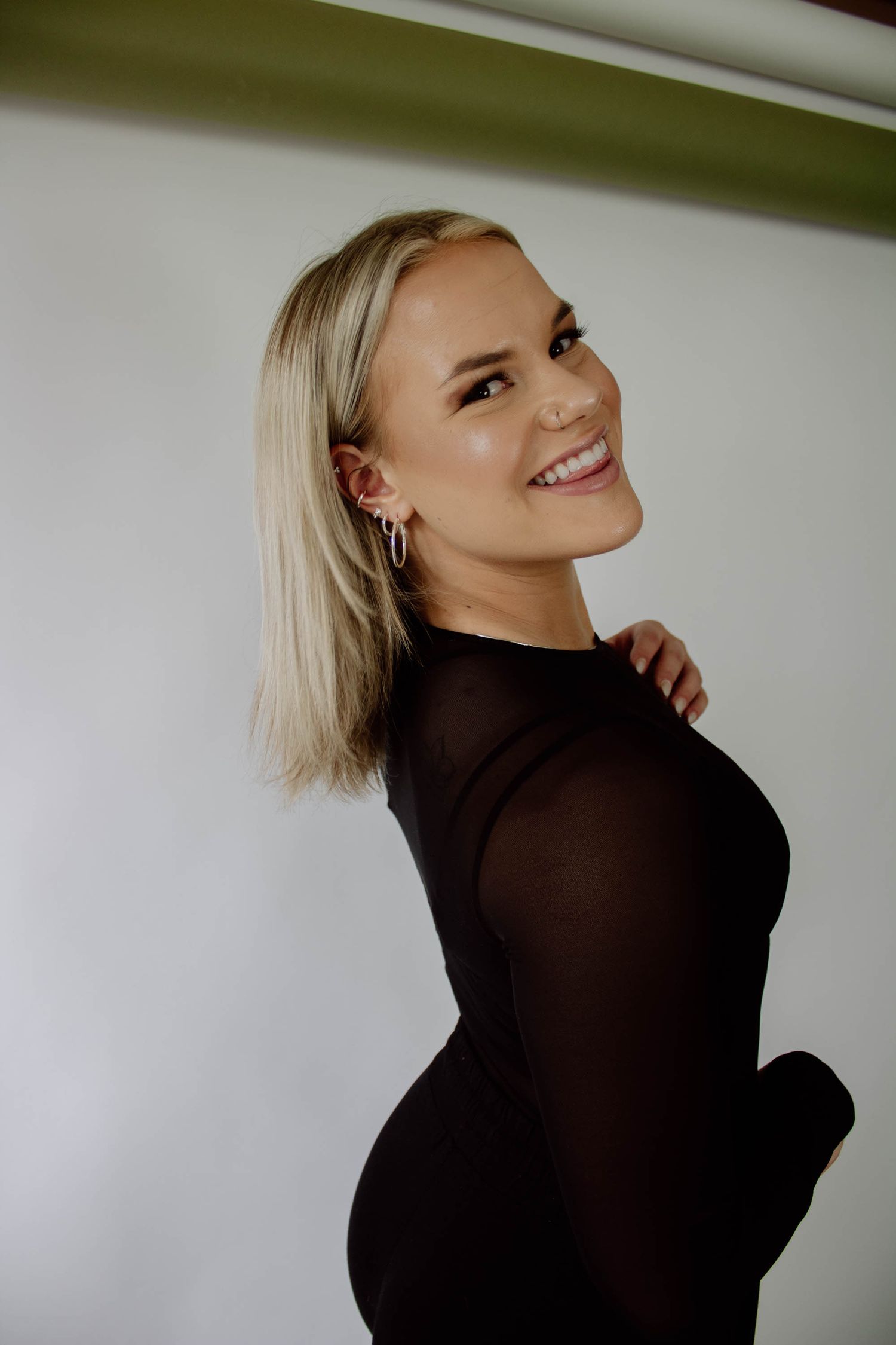 A person in a black long sleeve top poses against a white wall in a series of dynamic profile shots.